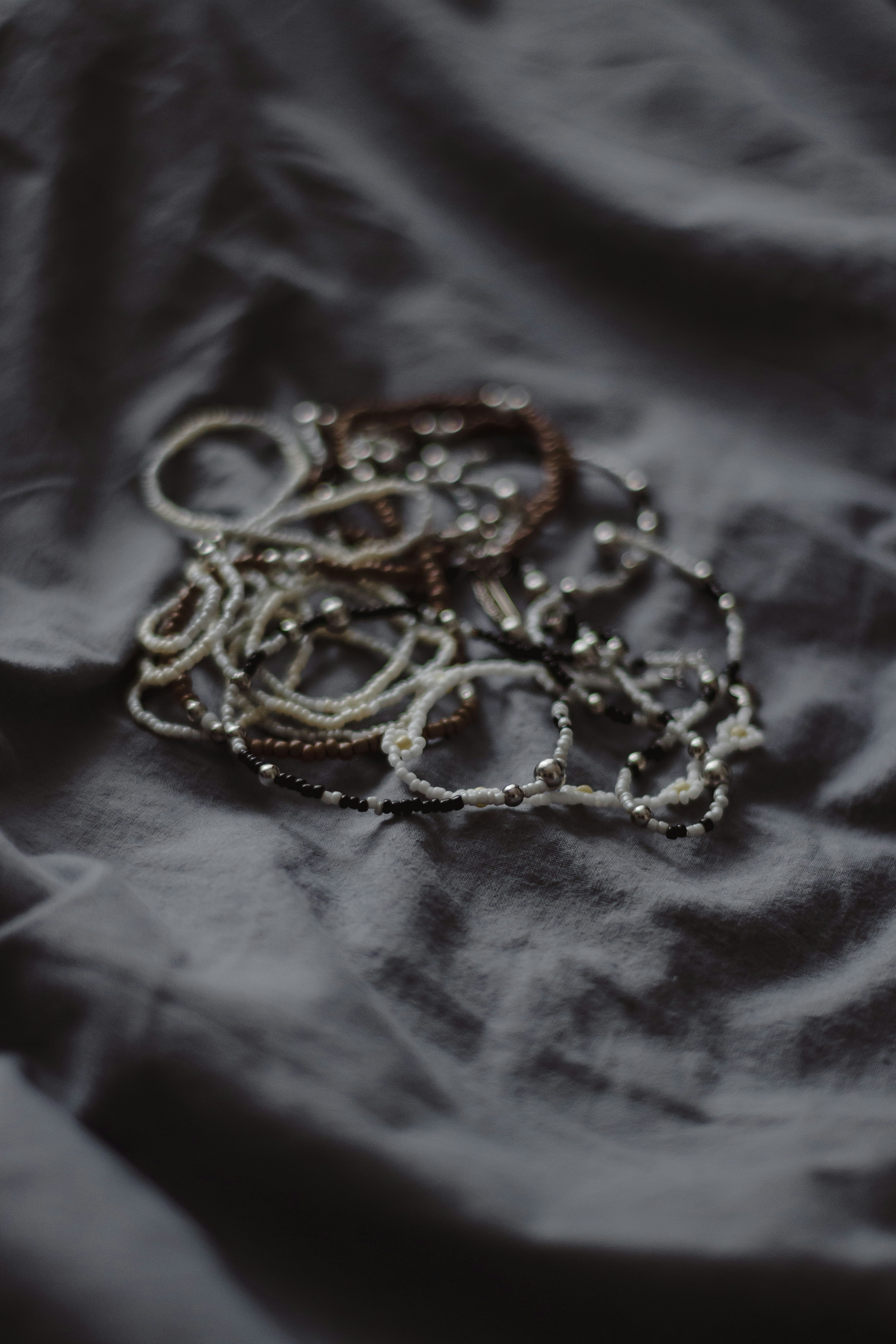 Bracelets and jewelry lie scattered on fabric.
