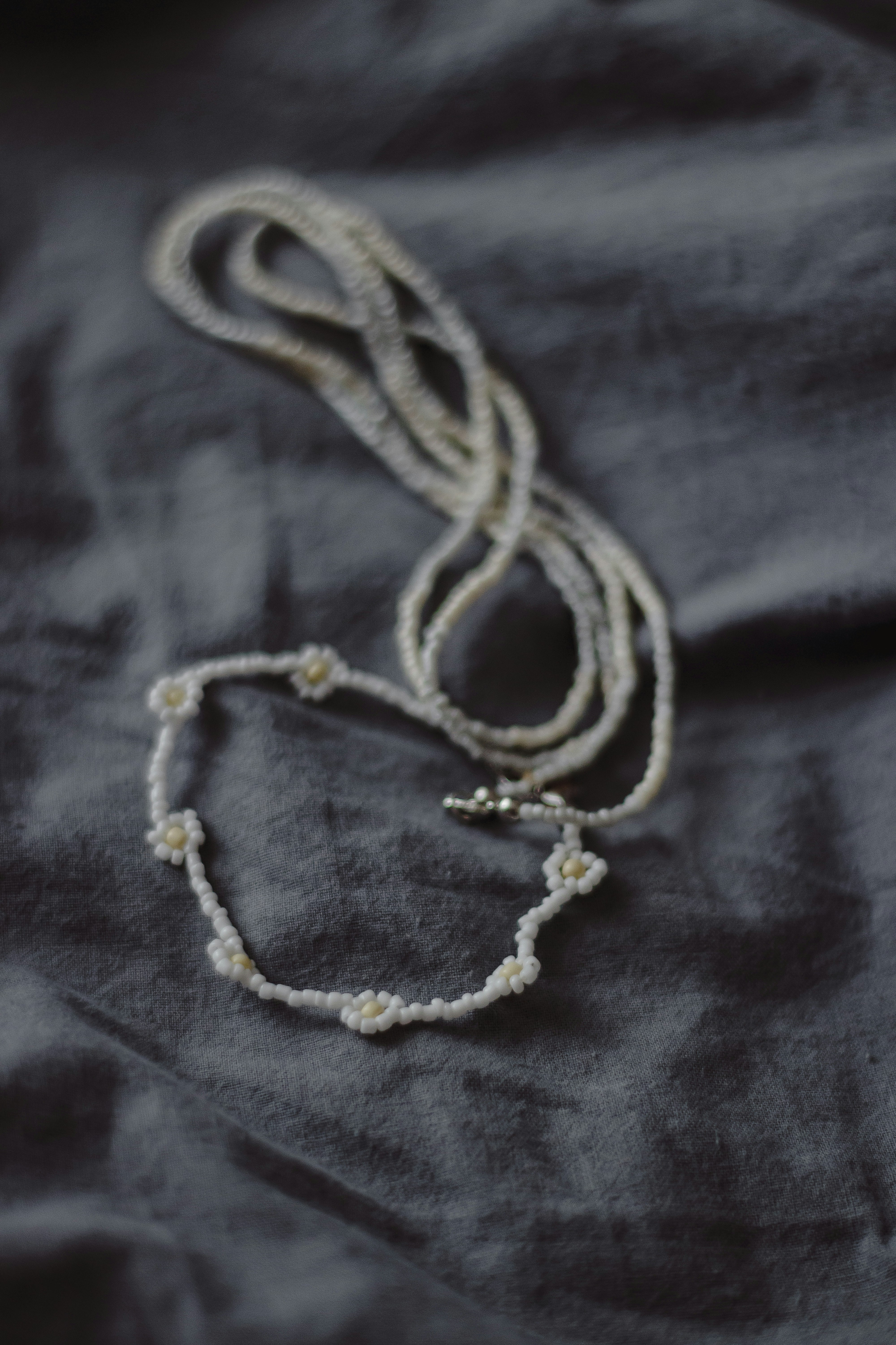 Un collier de perles orne un tissu gris.
