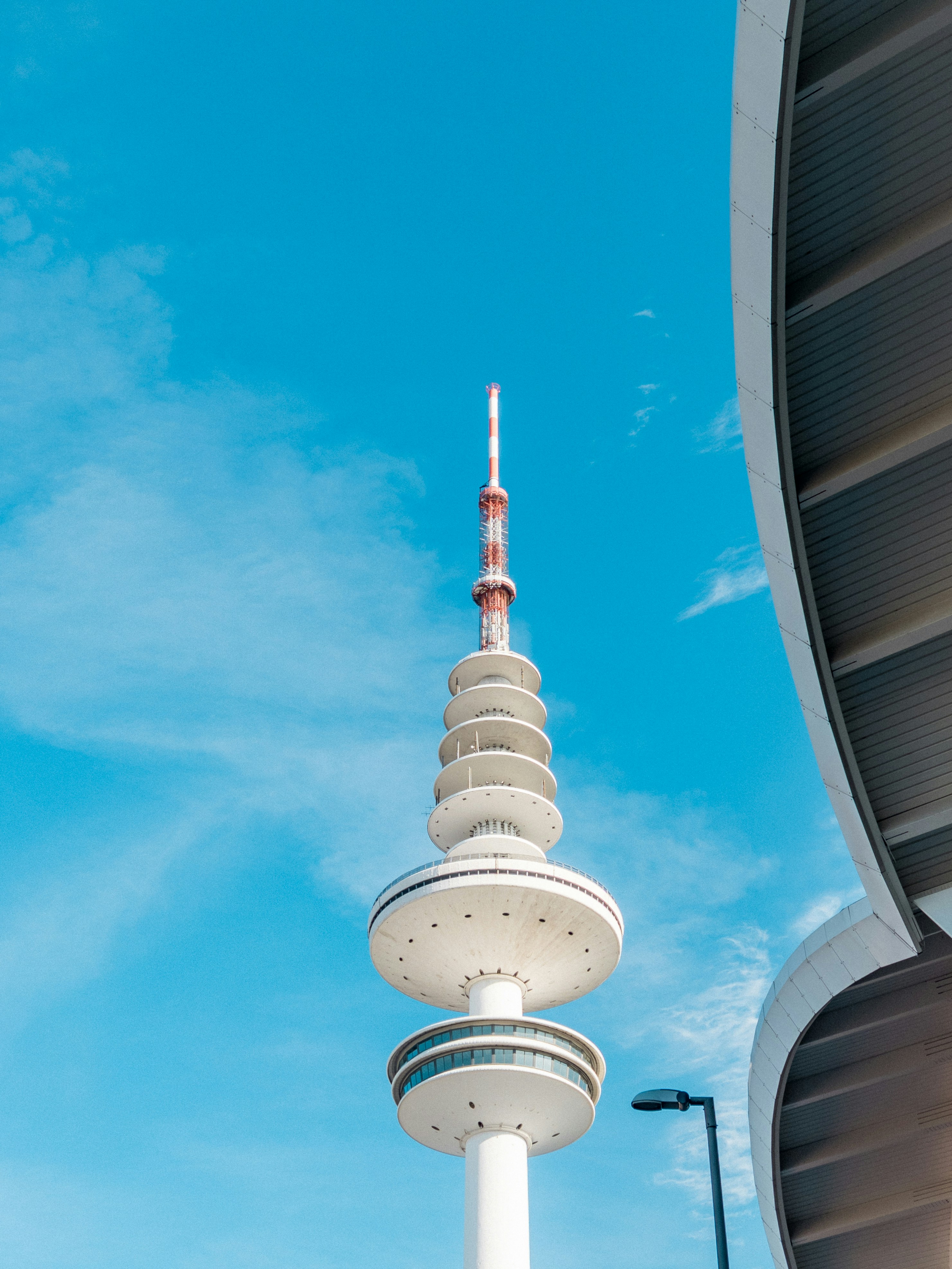 A tall, white tower pierces a blue sky.