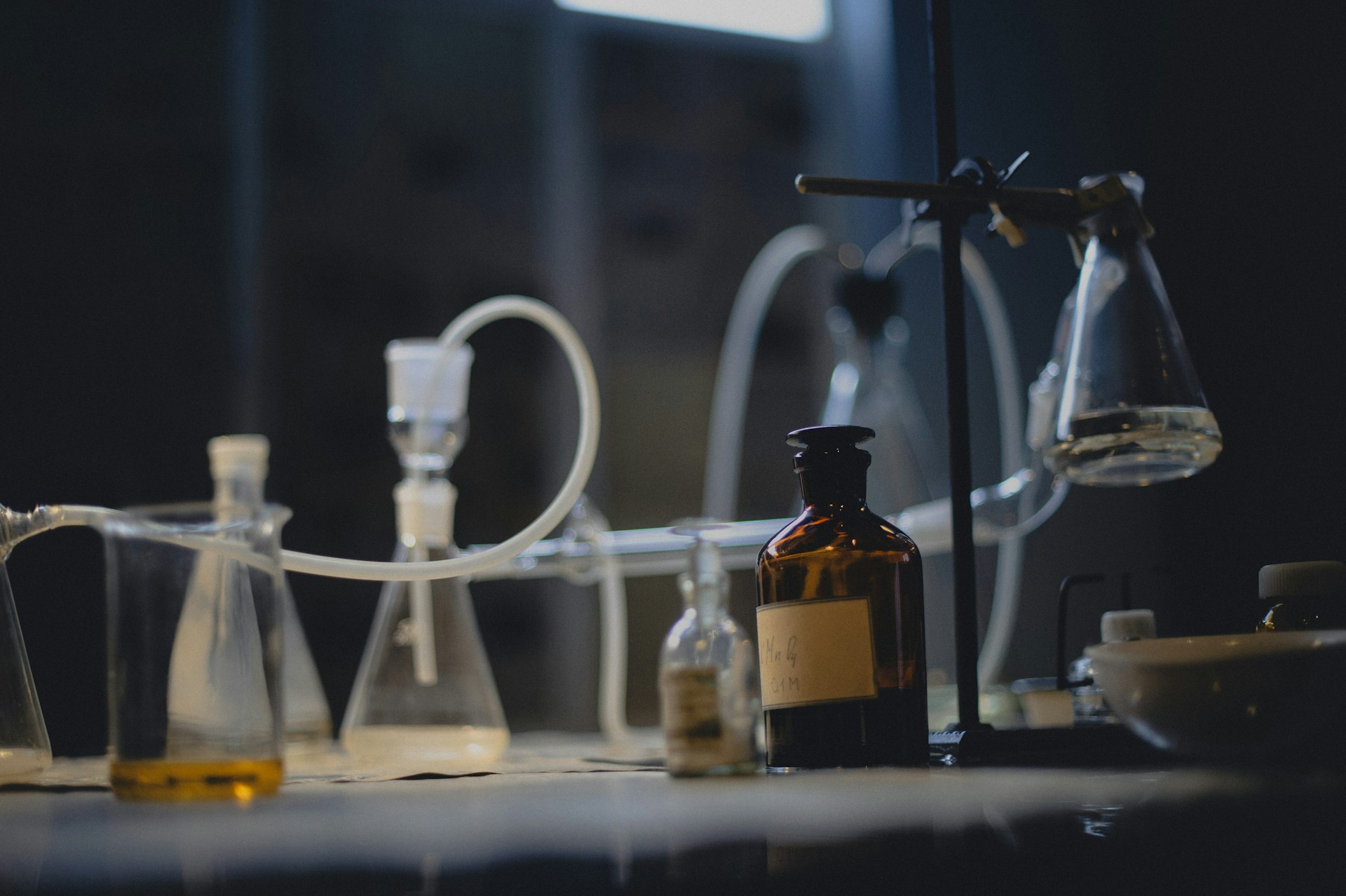 Laboratory glassware sits on a dark, illuminated table.