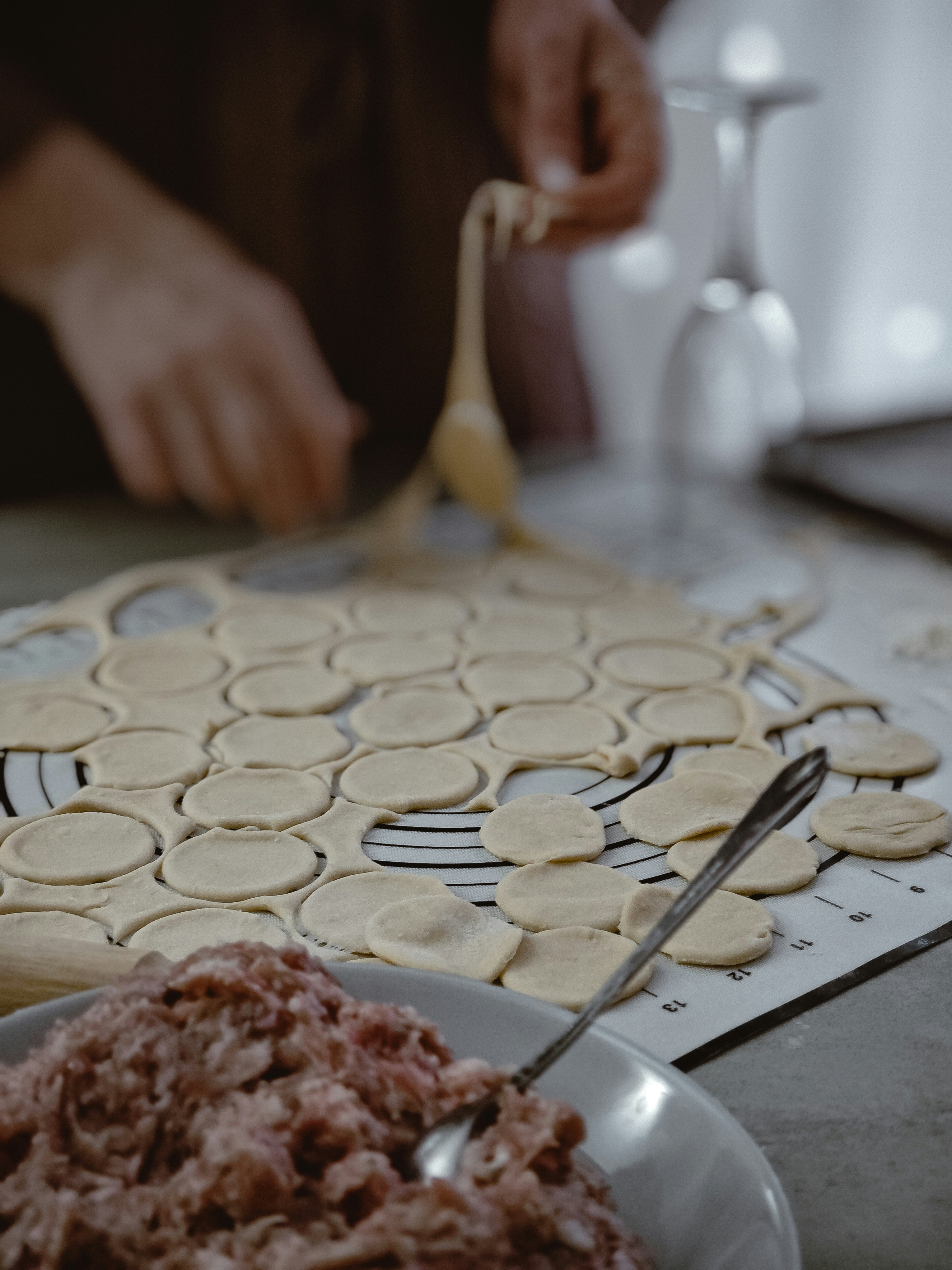 Dough circles and minced meat suggest a dumpling assembly.