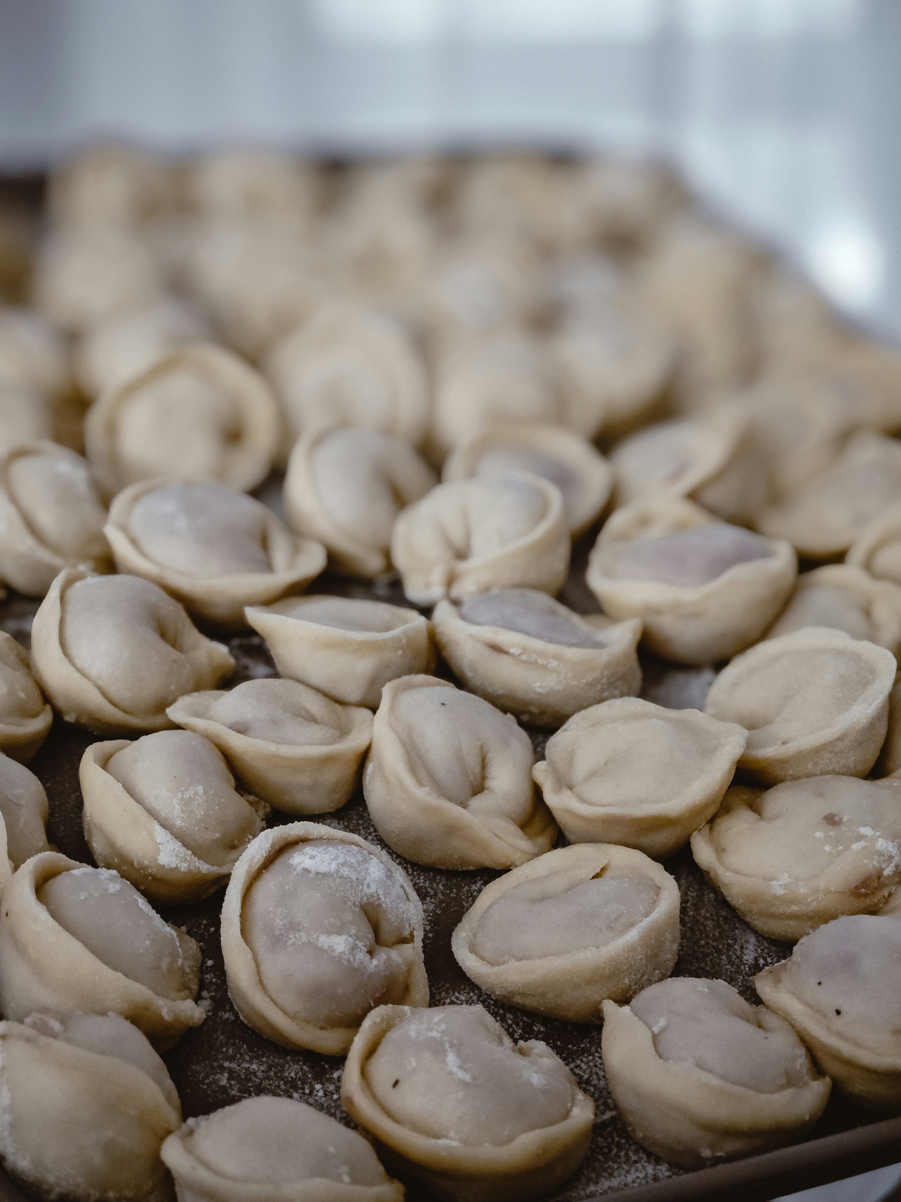 Raw dumplings sit on a baking sheet.