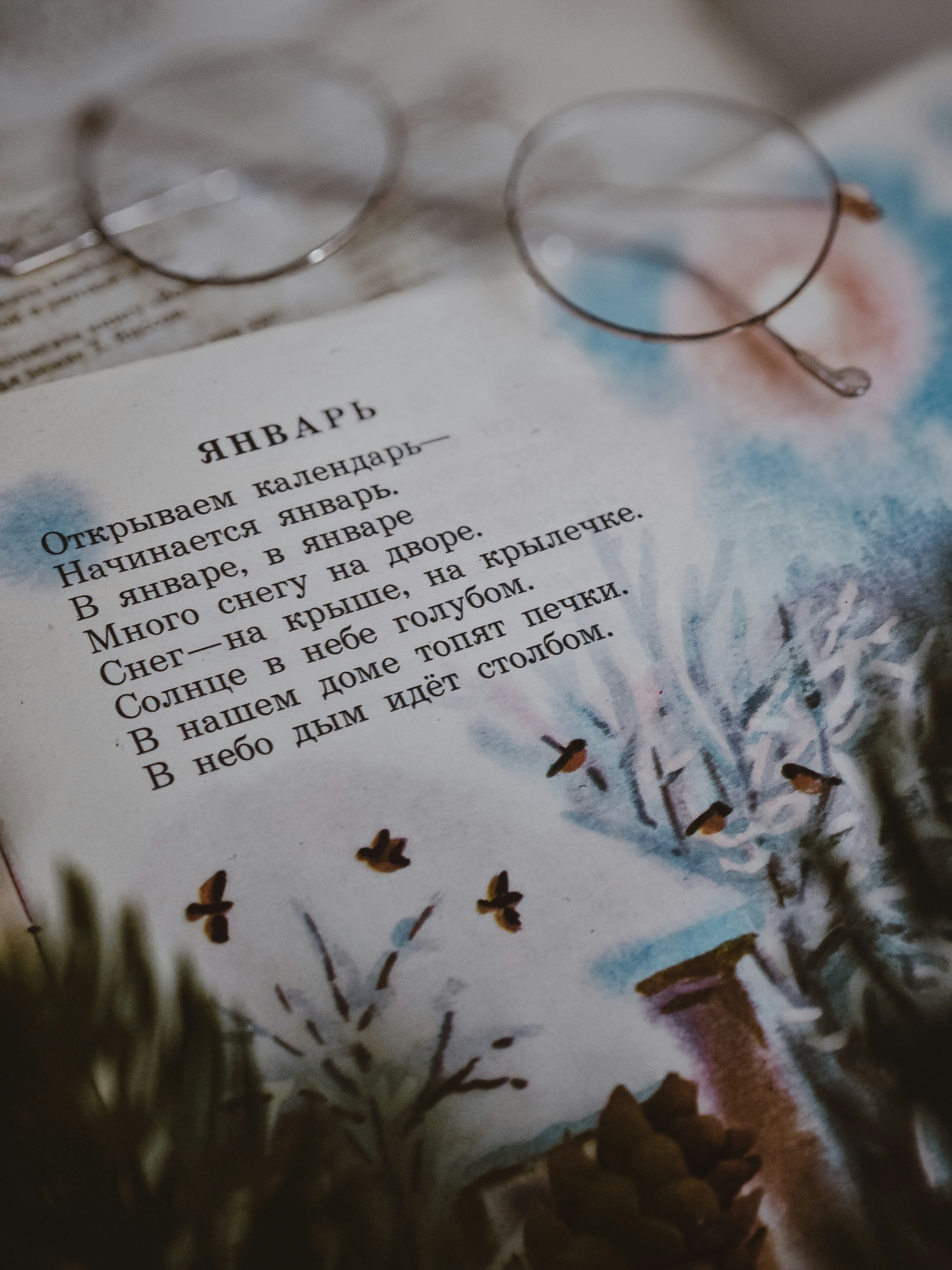 Glasses rest on an open book with illustrations.