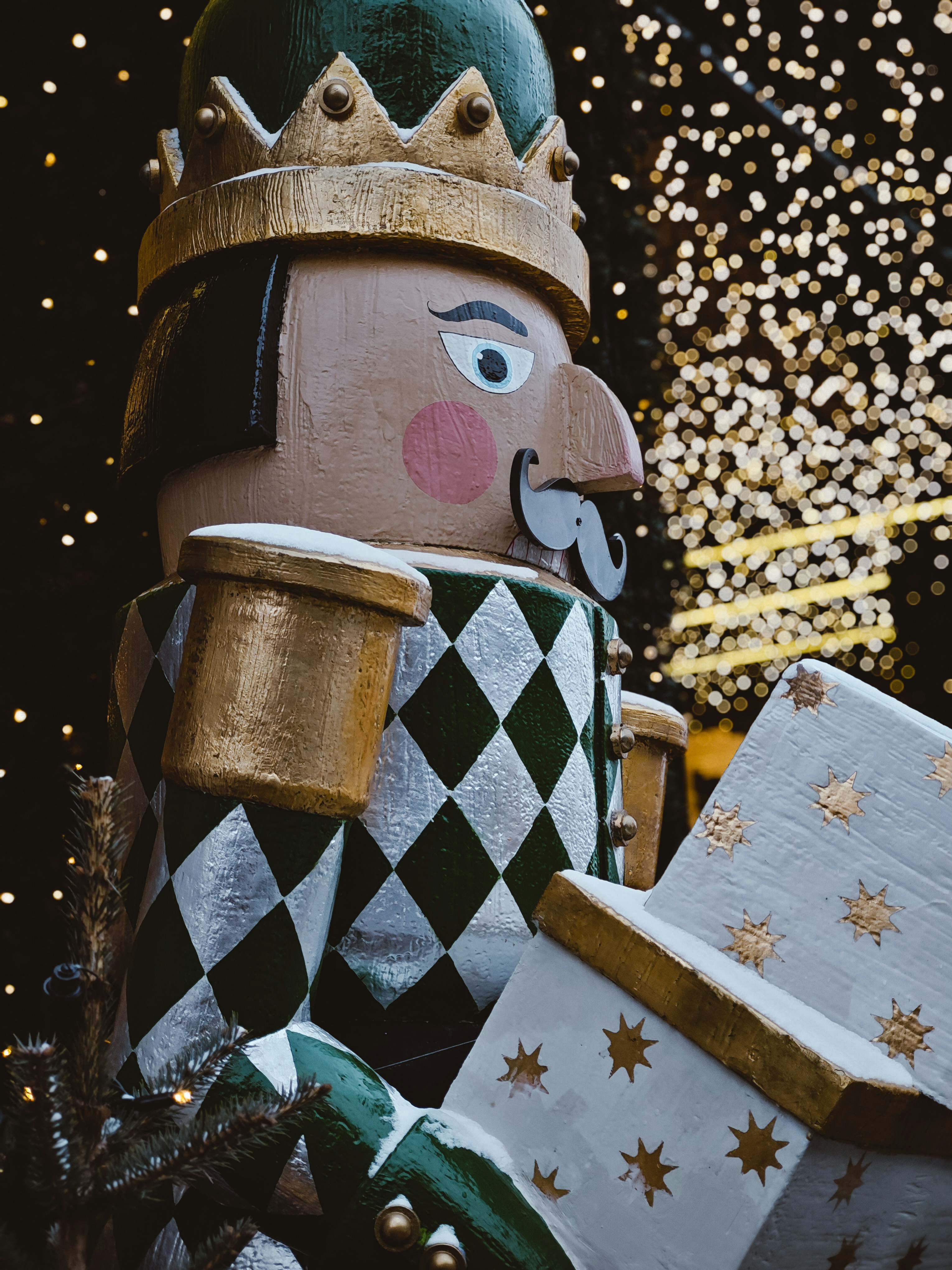 A nutcracker doll stands with a festive gift.