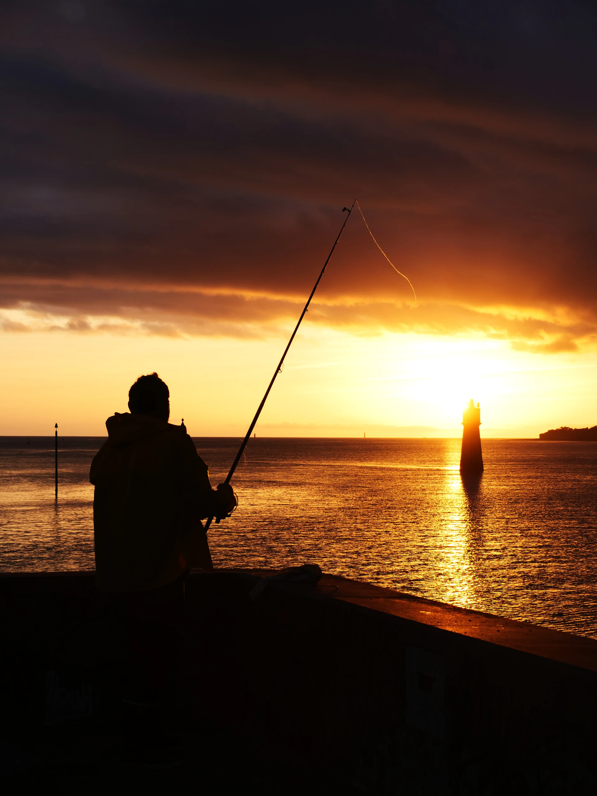 Pescador lançando a linha ao pôr do sol