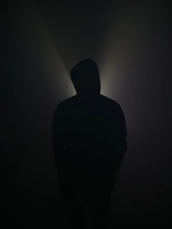A silhouette stands illuminated in the darkness.