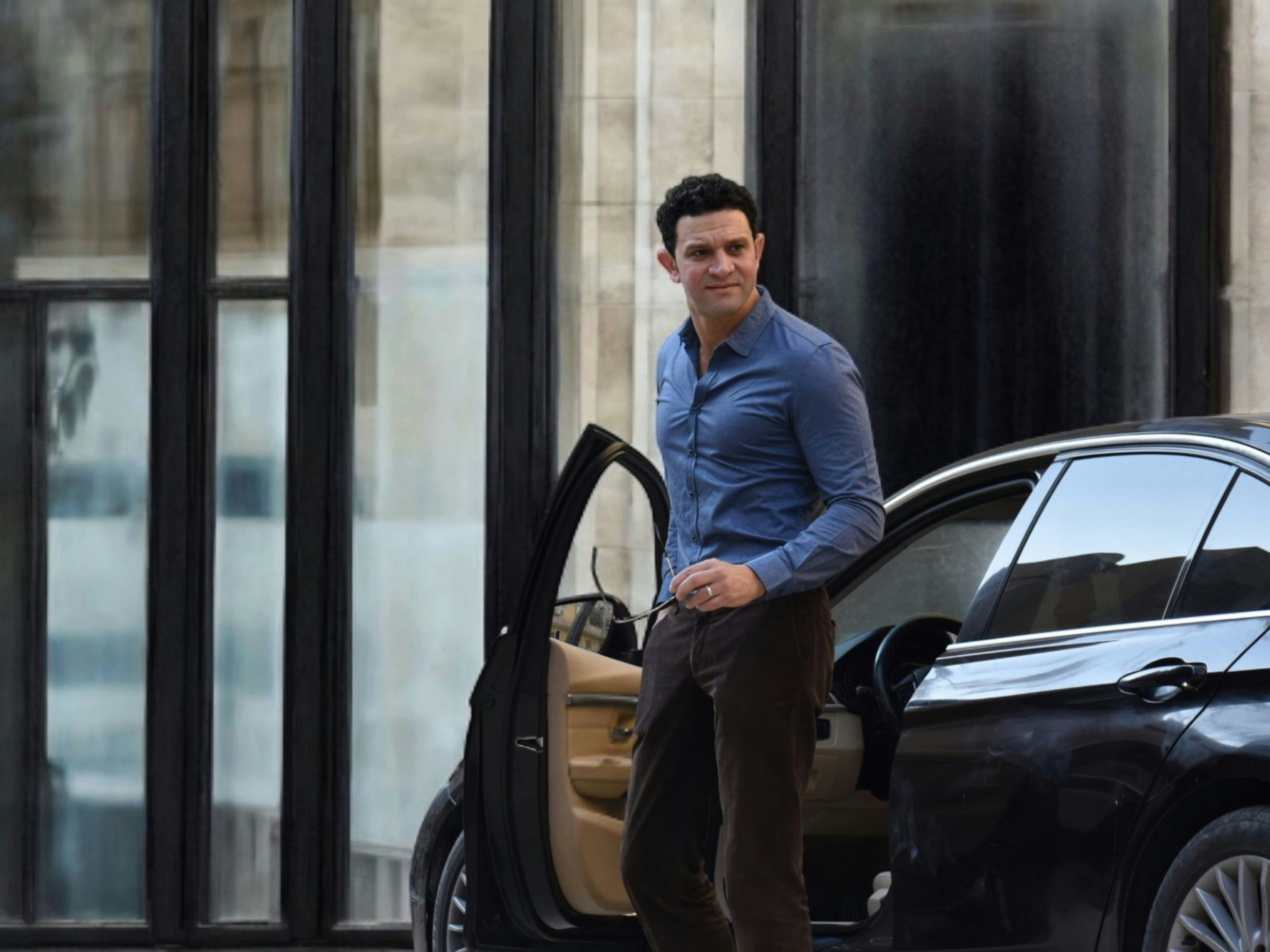 Man exits car in front of a building.