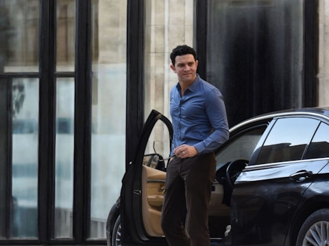 Man exits car in front of a building.