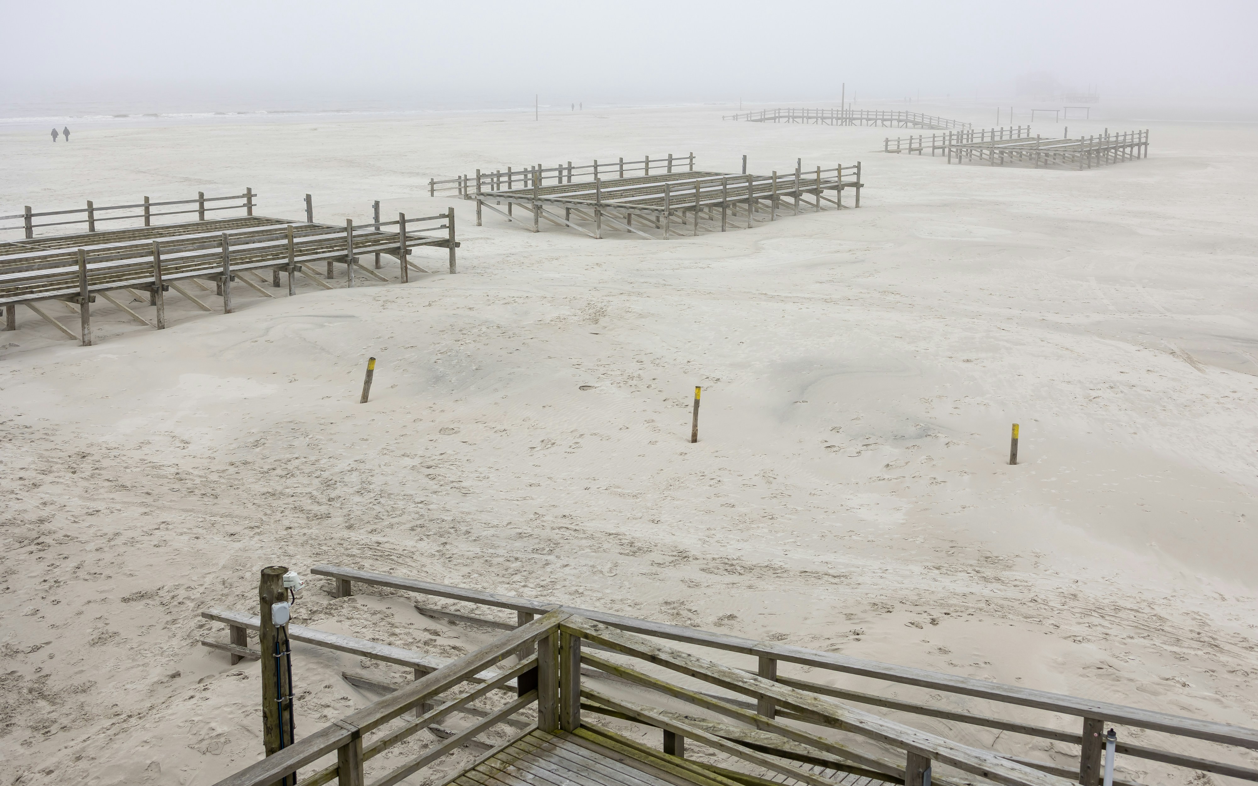 Foggy beach with wooden structures.
