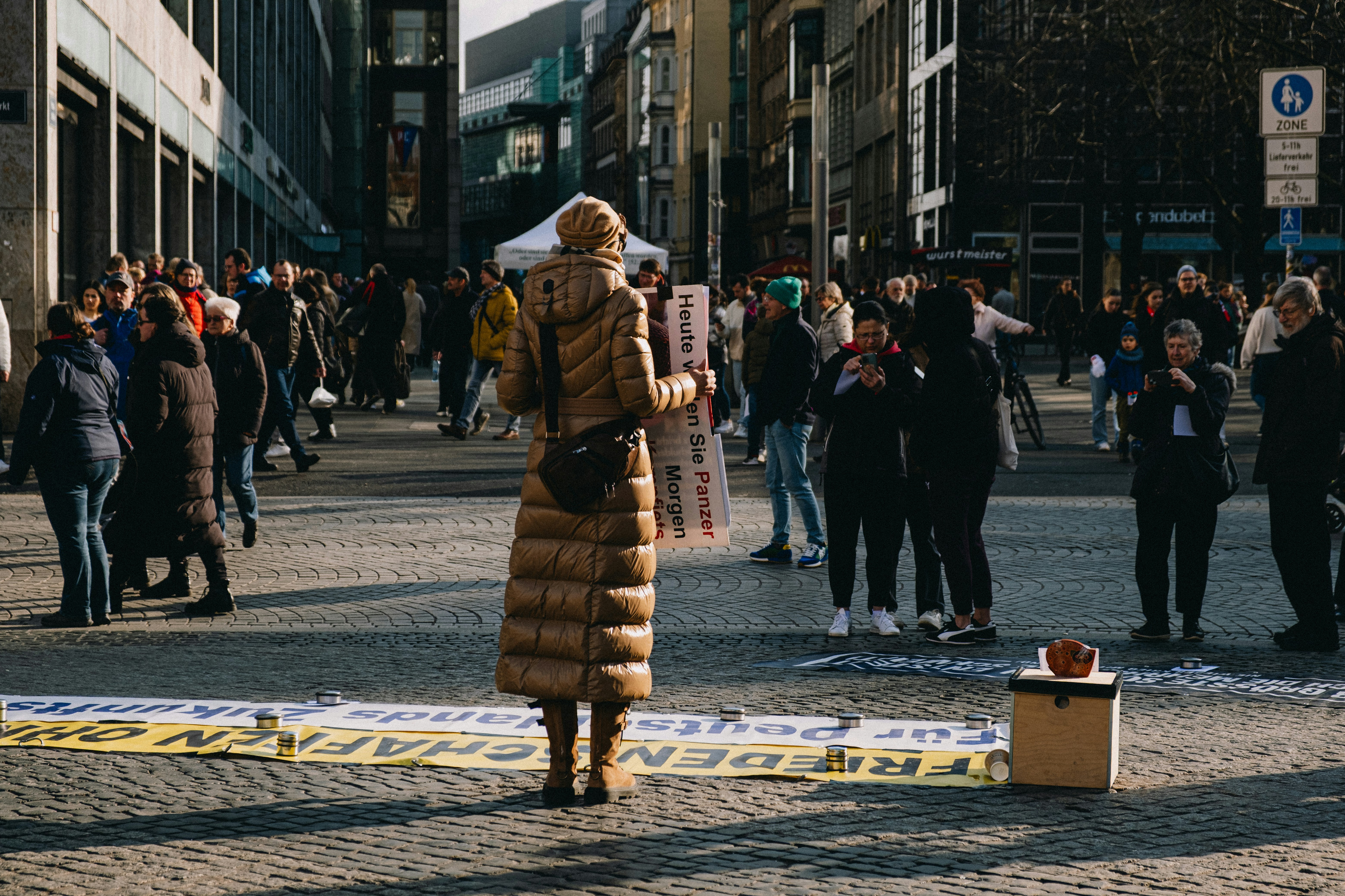 Protestor holds sign in a crowded city square.