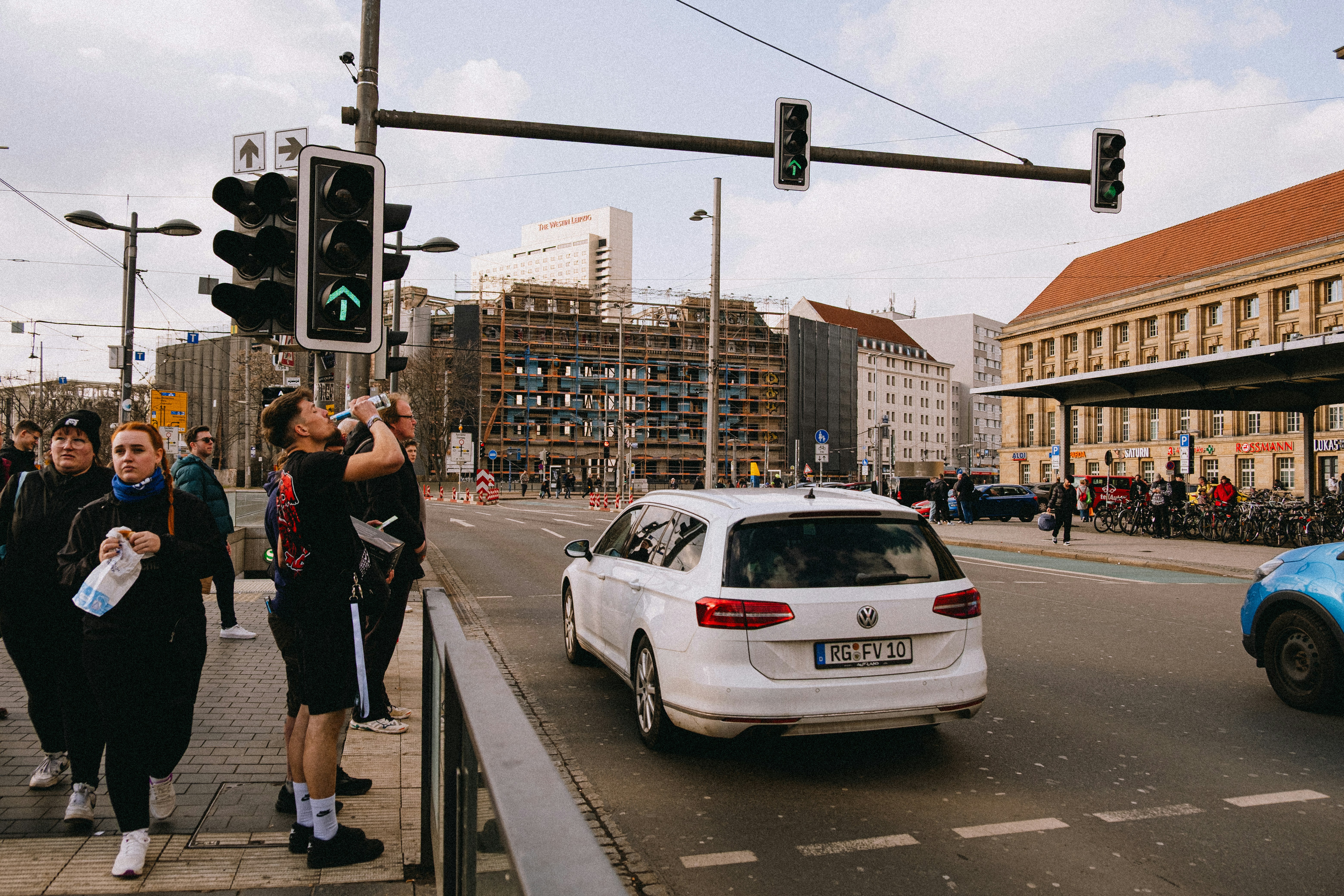 People wait at a traffic light in a city. (Photo by Ben Kupke on Unsplash)