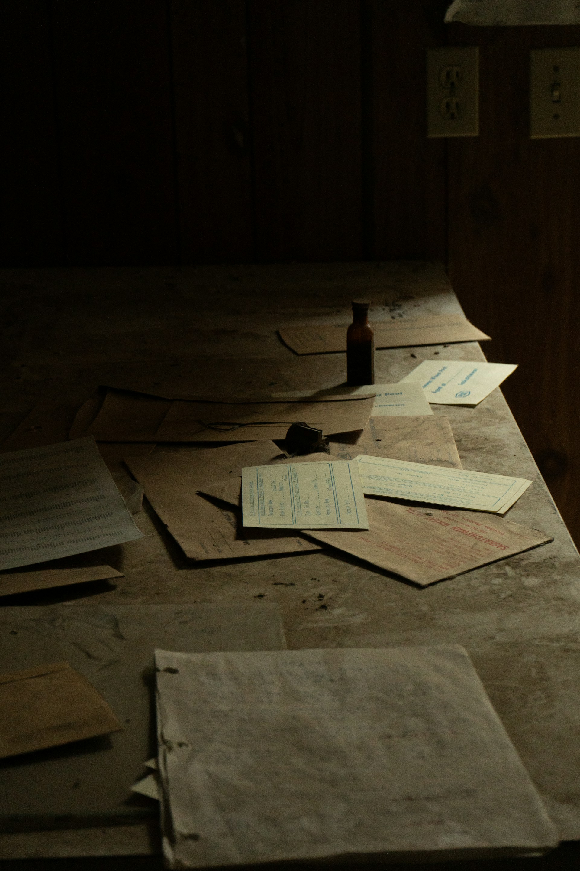 Papers and a small bottle rest on a dusty table.
