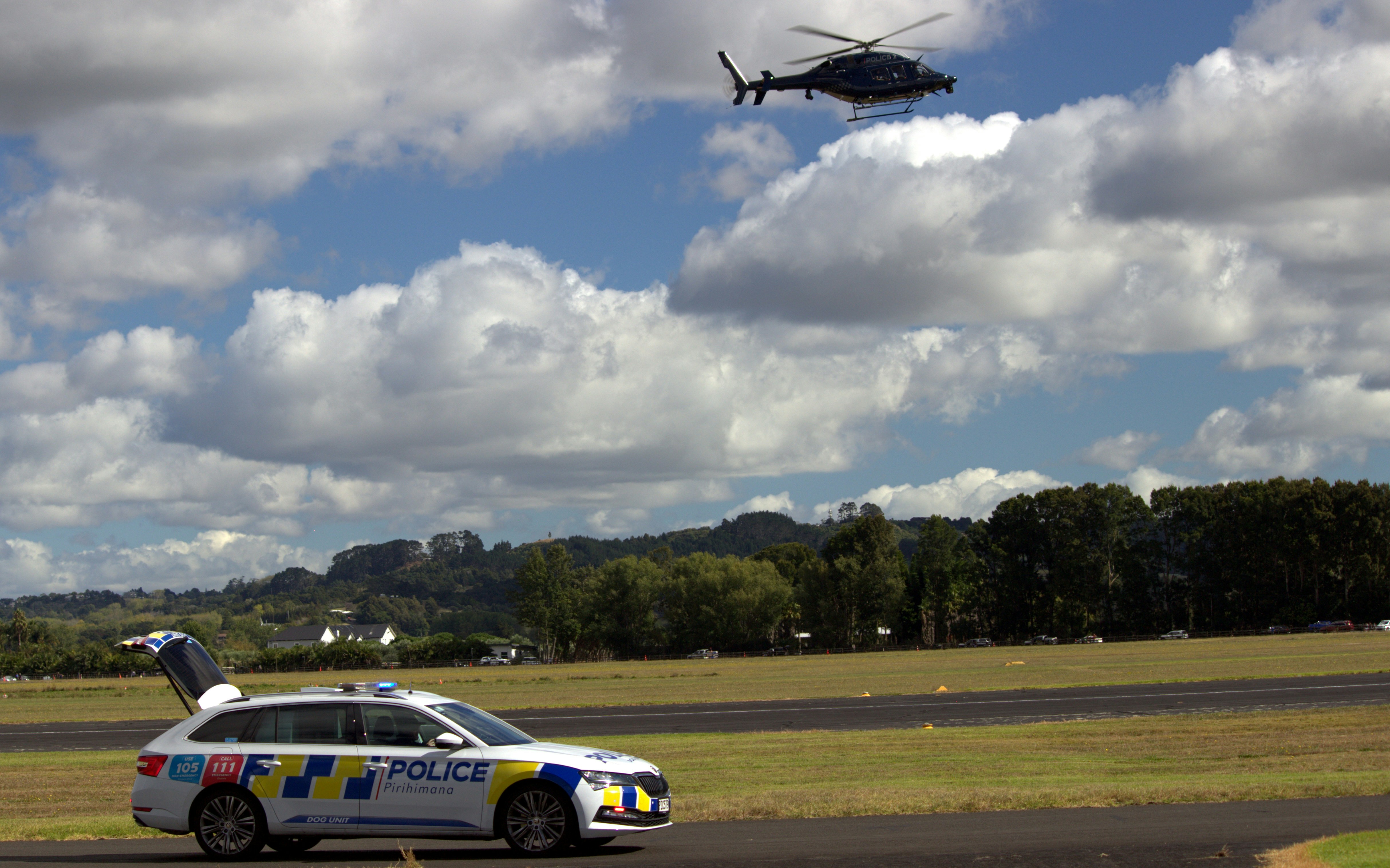 Police car on the ground with a helicopter above.