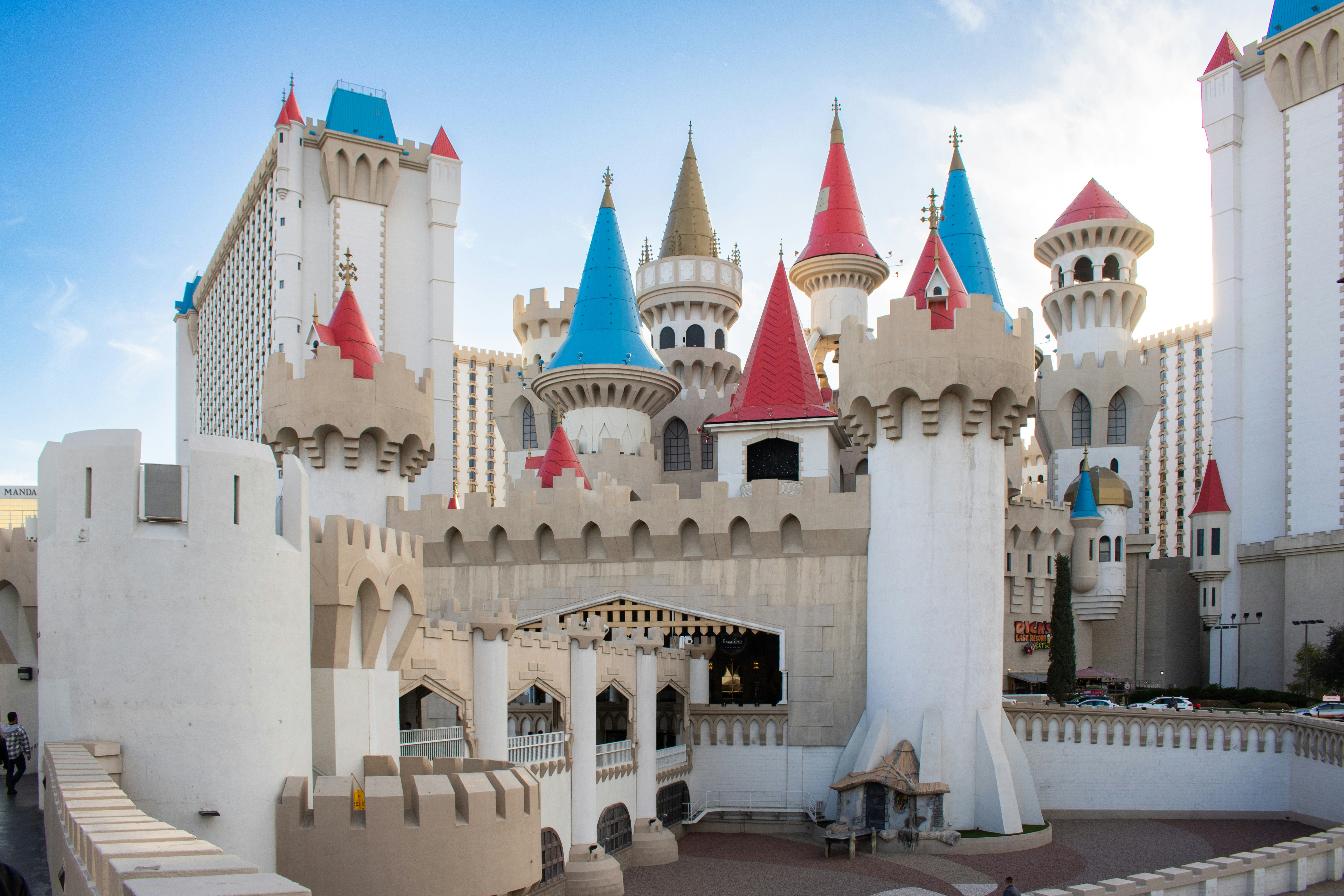 A castle-themed building with colorful towers., The Excalibur Hotel & Casino, located on the Las Vegas Strip, is a medieval-themed resort inspired by Arthurian legends. Opened in 1990, the hotel features a distinctive castle design with colorful turrets and a fortress-like facade. It spans 70 acres and originally had over 4,000 rooms, making it one of the largest hotels in the world at the time. The property includes a casino, multiple restaurants, and entertainment venues. Positioned at the intersection of Tropicana Avenue and Las Vegas Boulevard, it remains a prominent fixture in Vegas tourism.