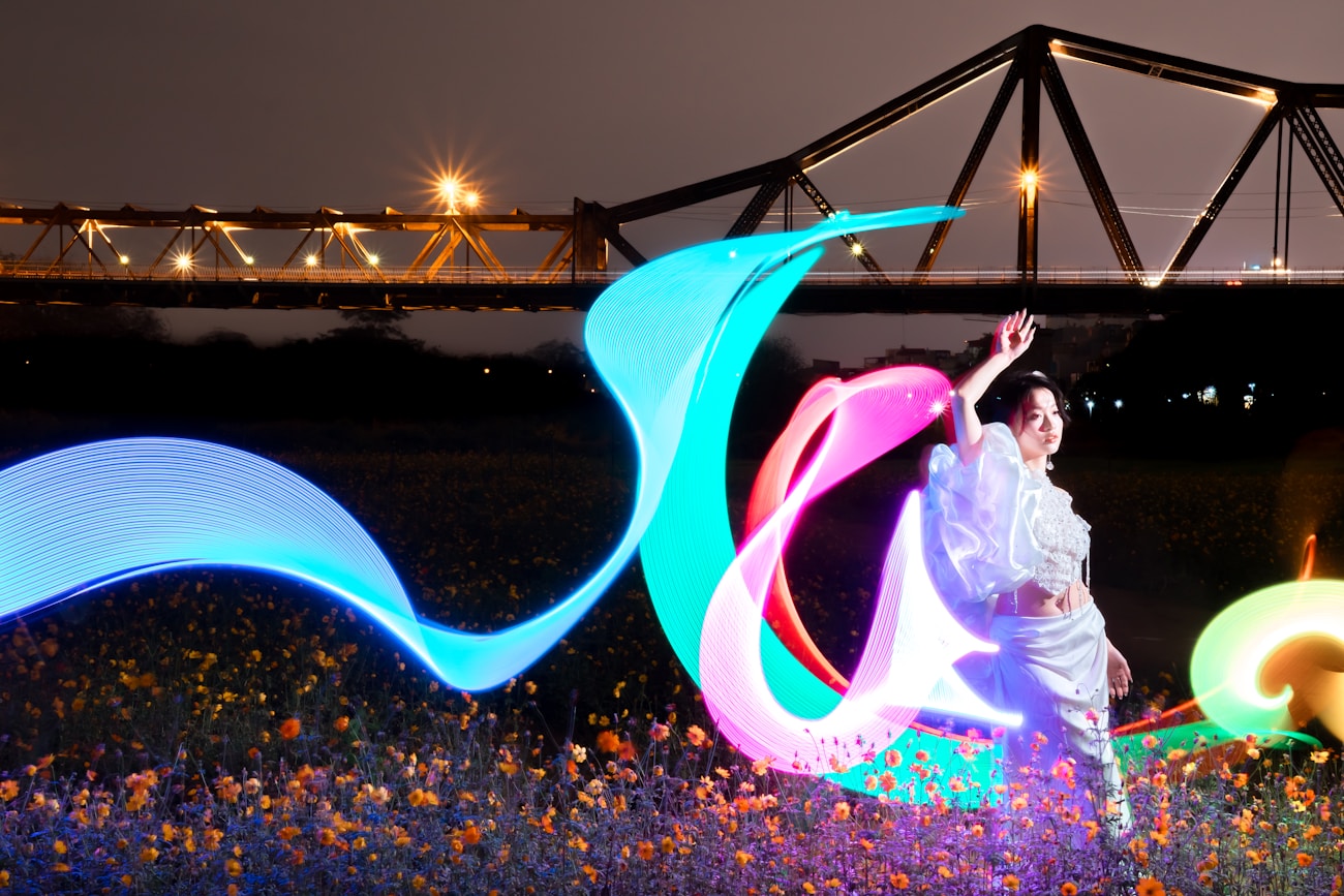 Dancer creating colorful light trails through long exposure light painting photography