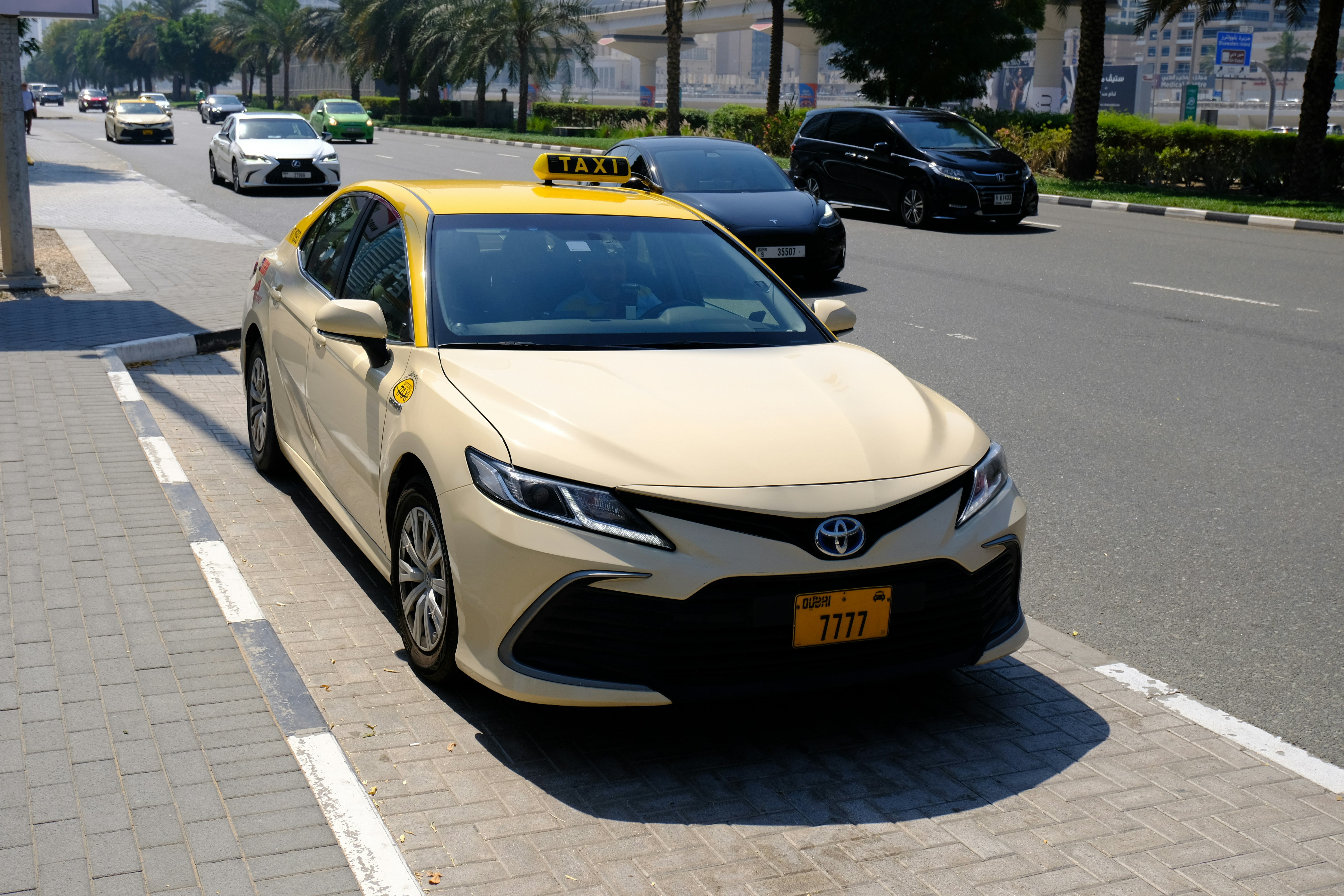 A taxi rests on the side of the road.