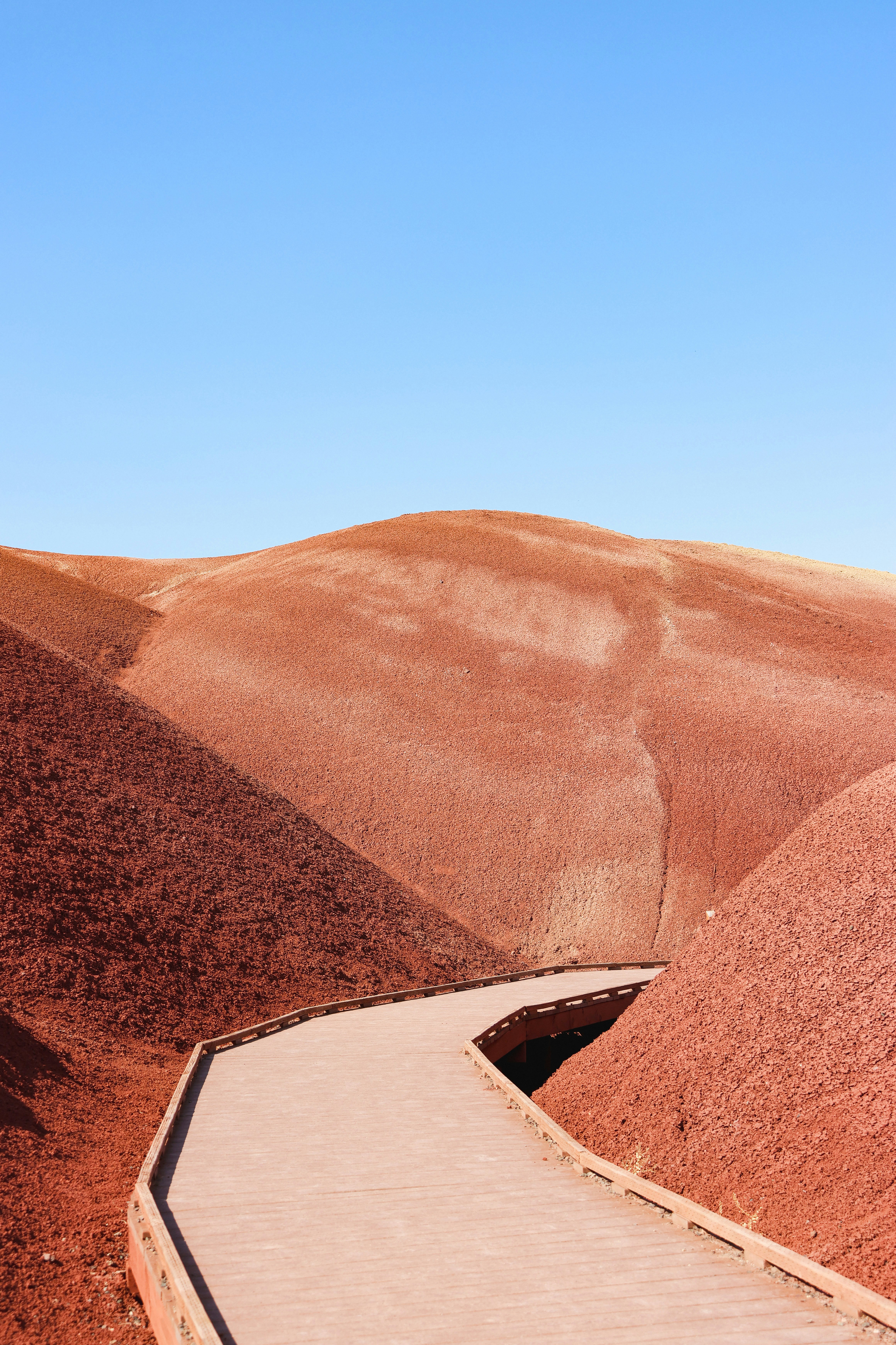 A winding walkway through red, rolling hills.