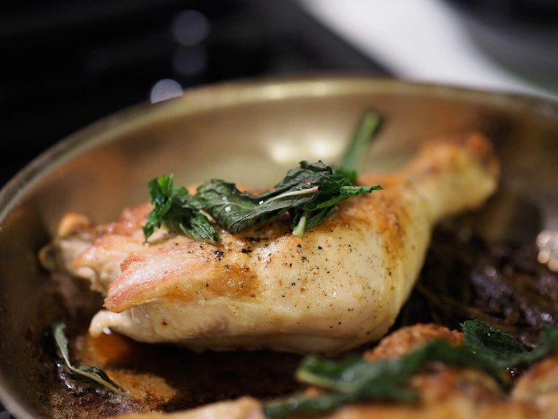 Roasted chicken is garnished with herbs in a pan.