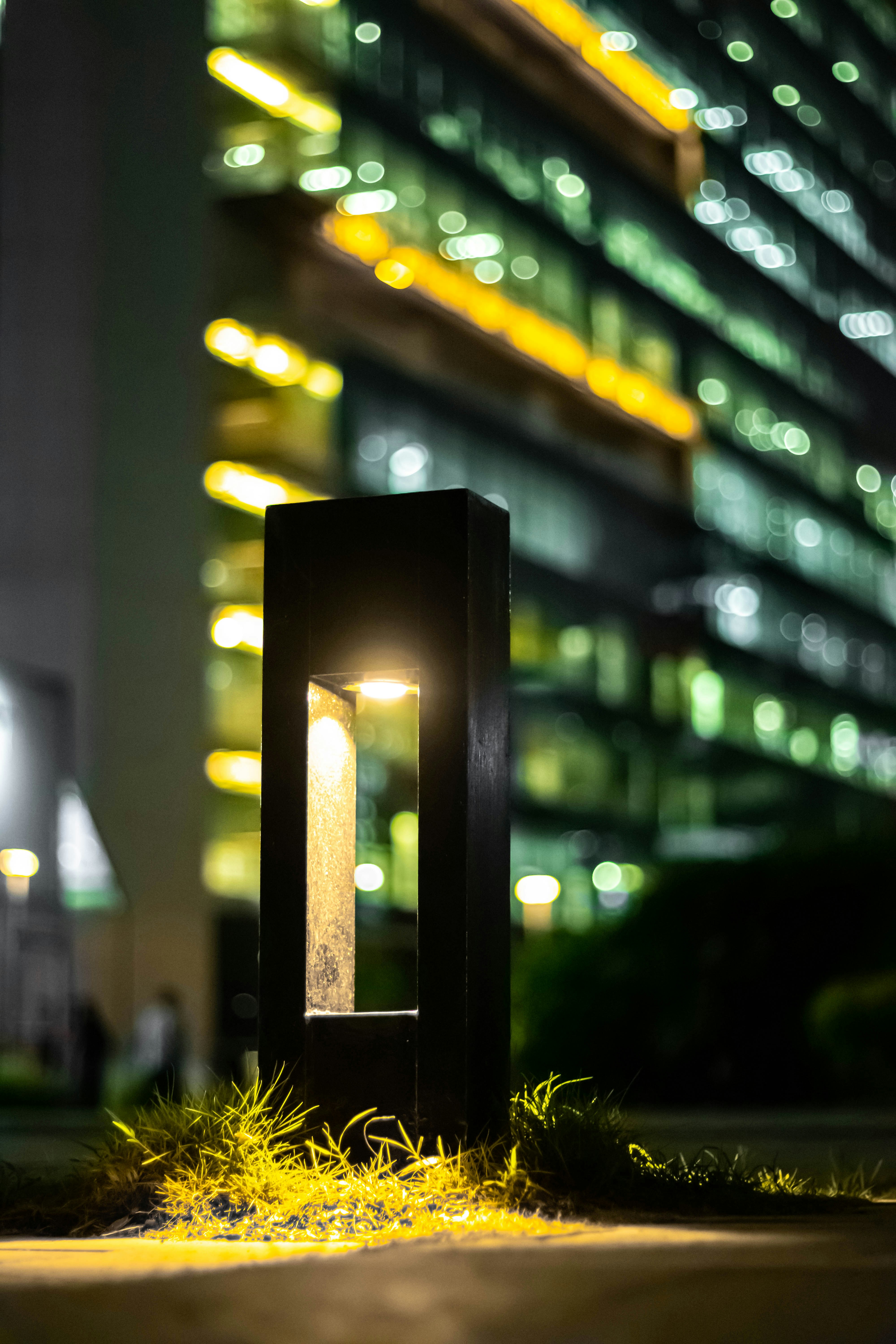 A lit outdoor lamp with a bright office building.
