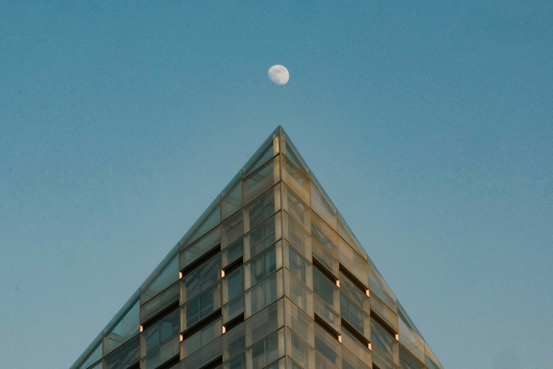 Moon hovers above a pyramid-shaped building.