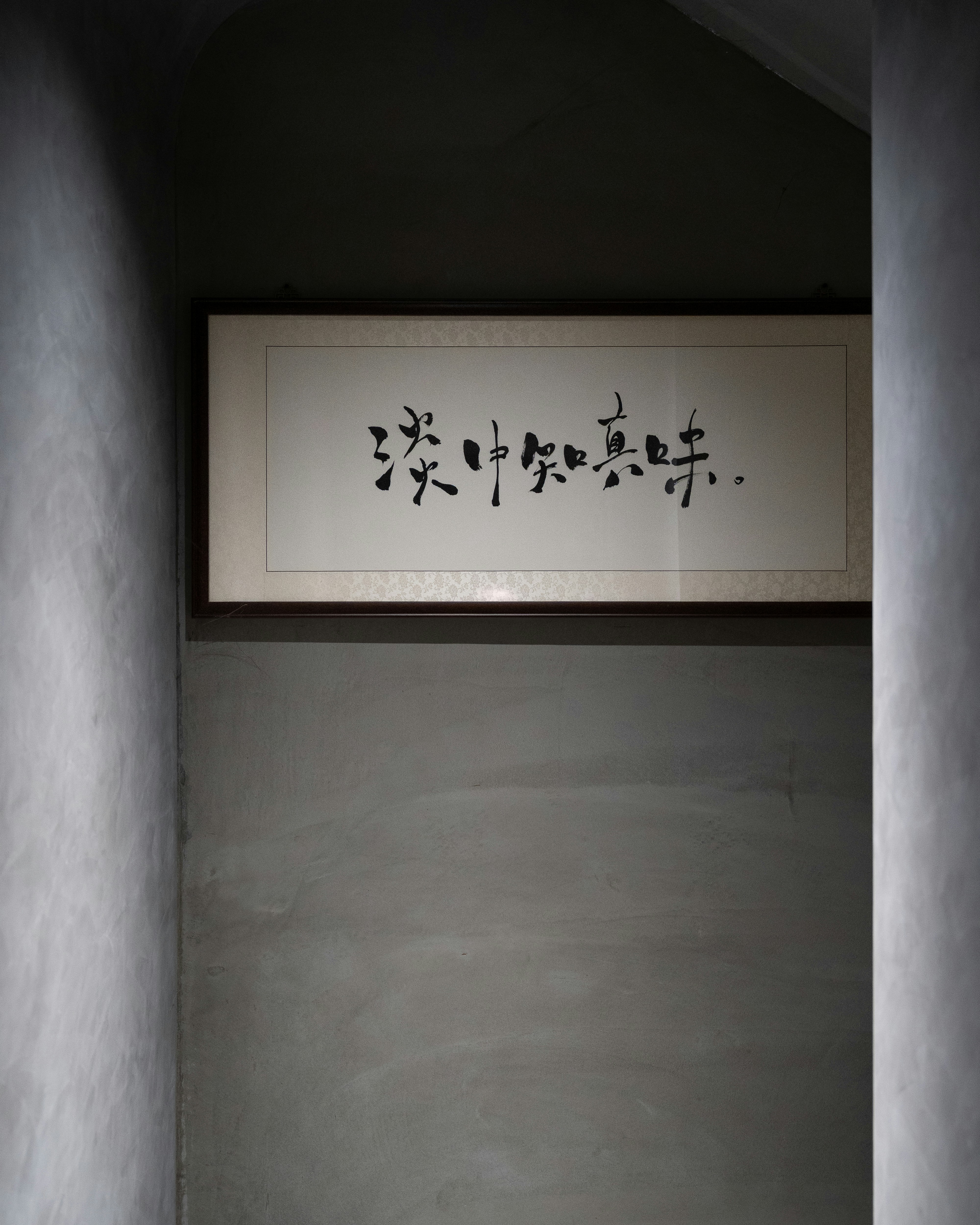A framed calligraphy hangs on a gray wall. photo – Free Text Image on ...