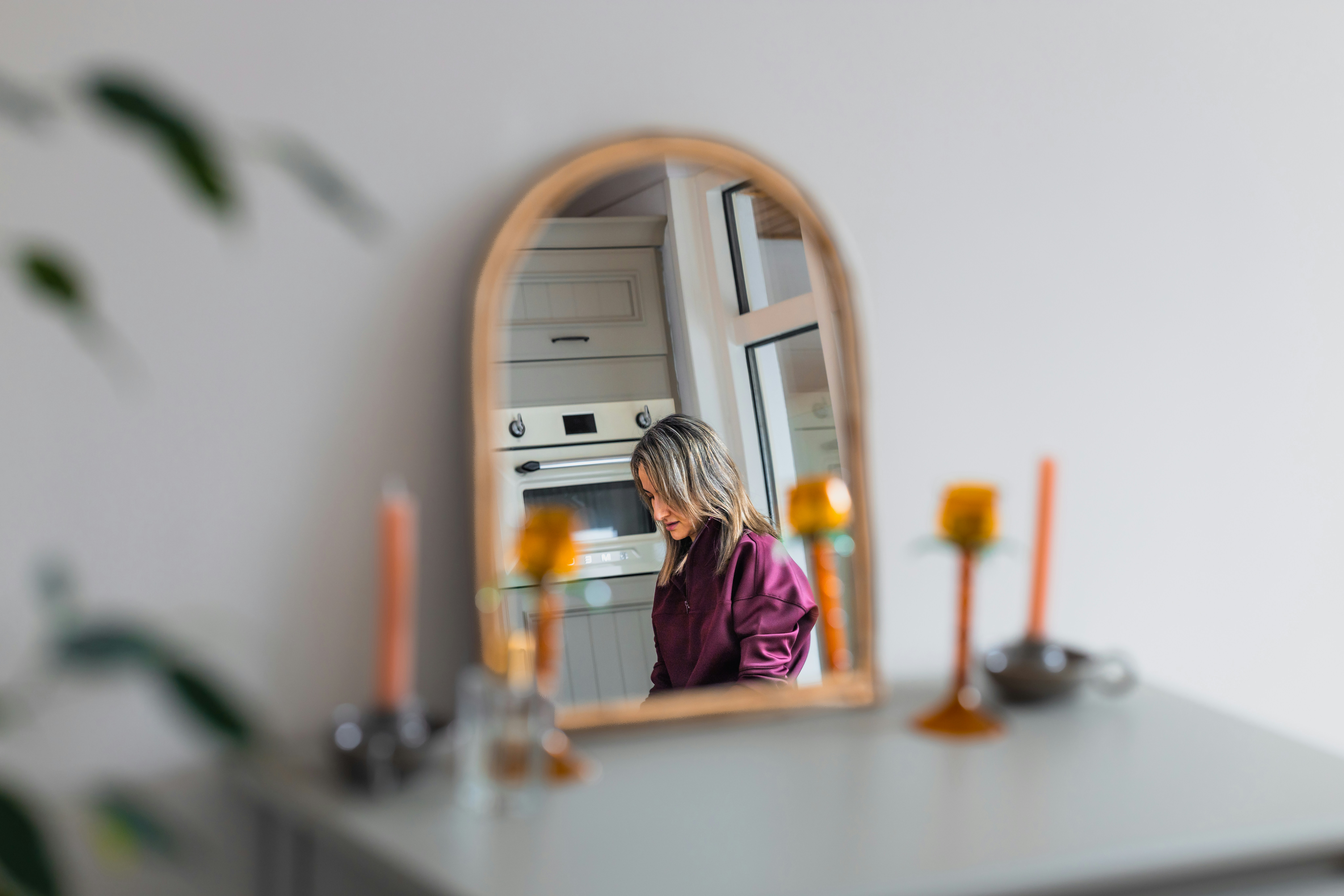 Woman reflected in a wooden arched mirror