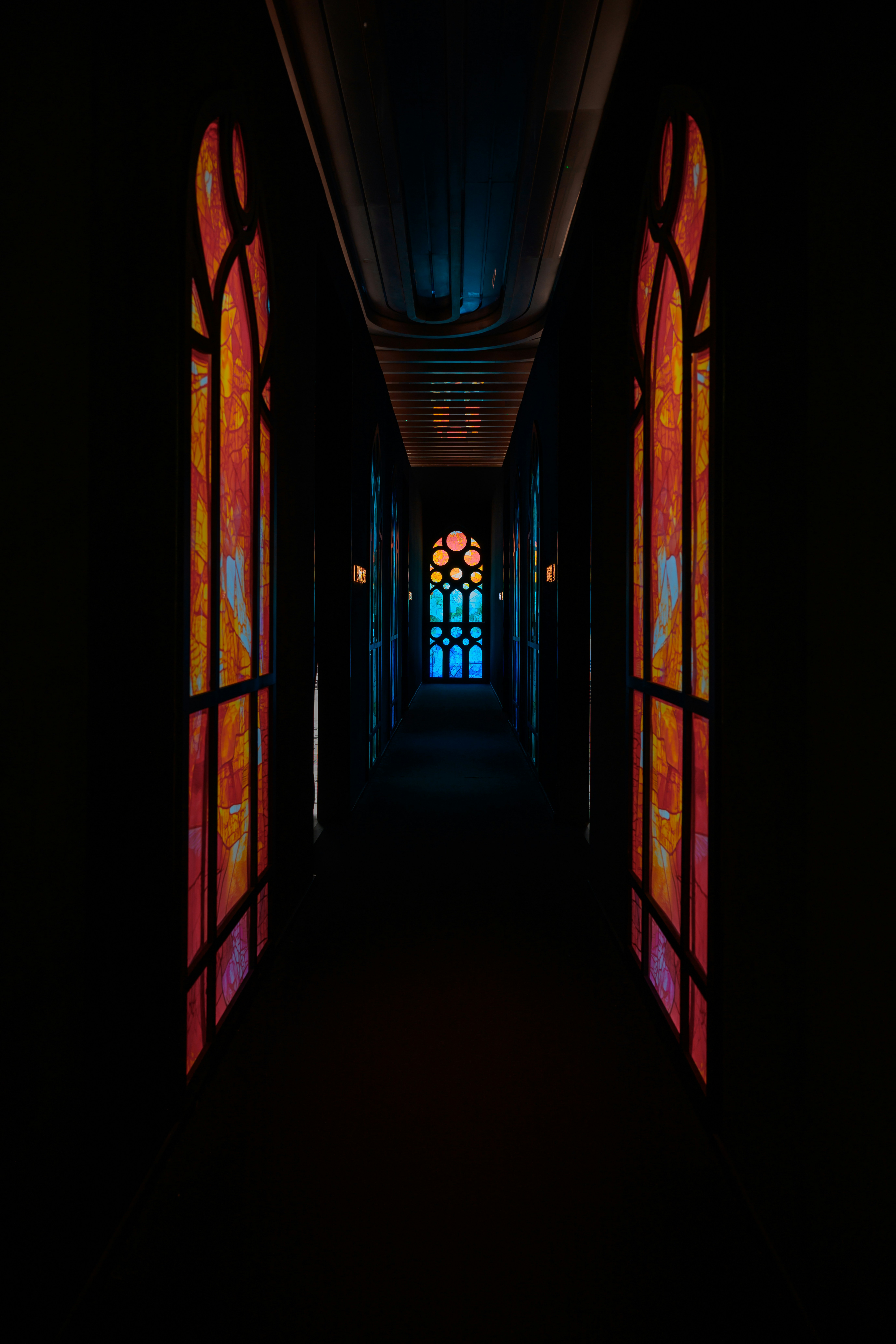 Dark corridor with stained glass windows.