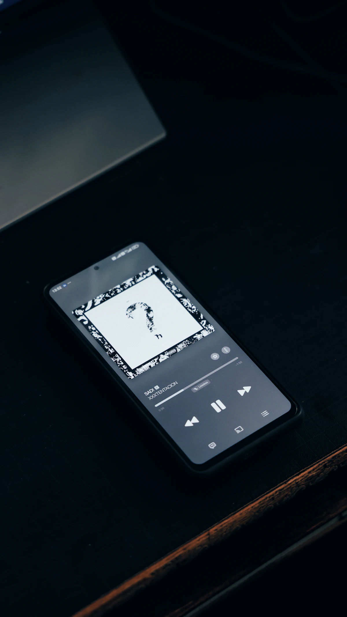Ponsel pintar menampilkan aplikasi musik di permukaan gelap menggambarkan lagu trending yang sedang naik di chart TikTok Mei 2026