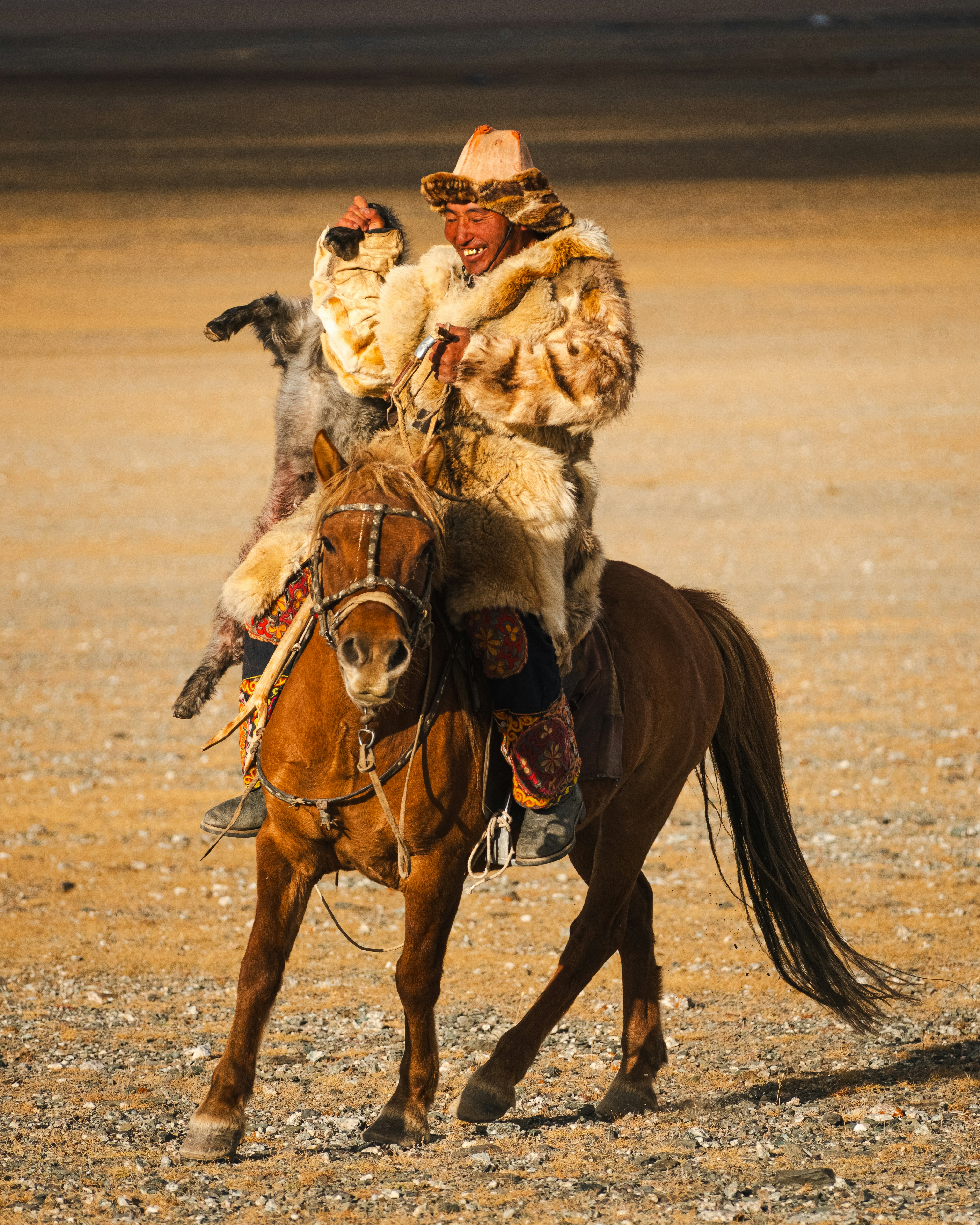 Mongolian man on horseback holding a prey.