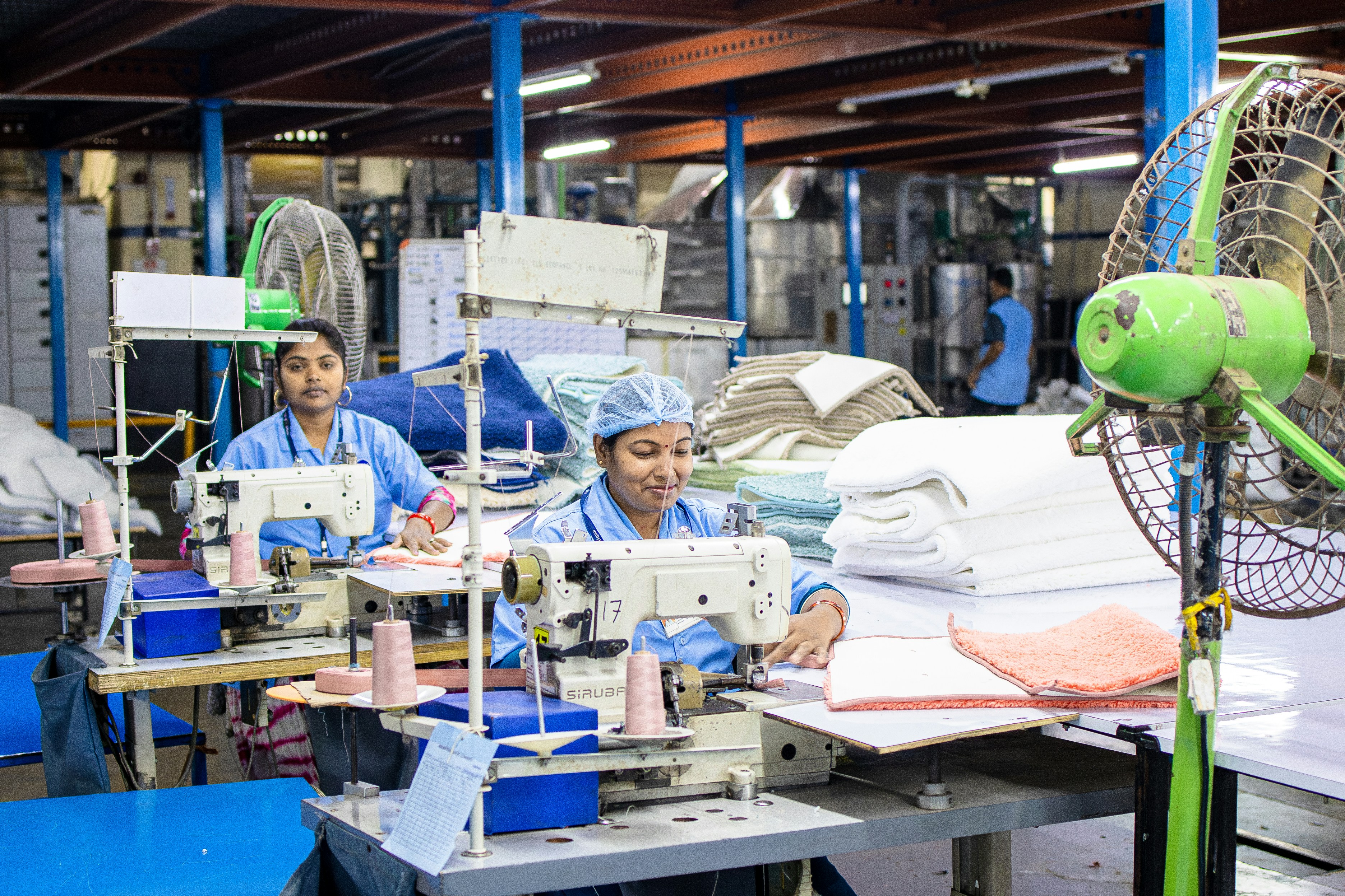 Workers operate sewing machines in a factory.