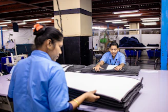 Factory workers folding fabric inside a garment factory.
