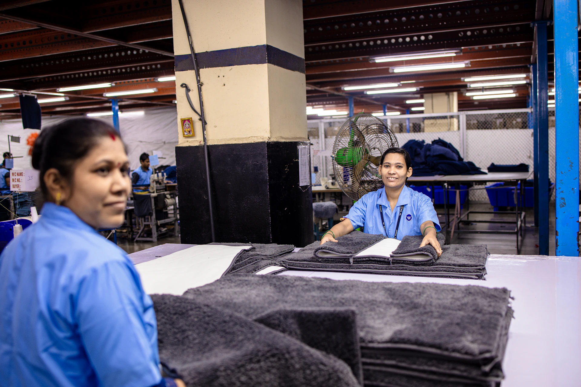 Workers are folding textiles in a factory setting.