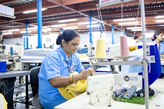 A woman sews fabric in a garment factory.