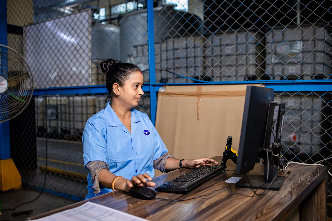 A staff member working at a computer in a stockroom, reconciling what each delivery vehicle is carrying
