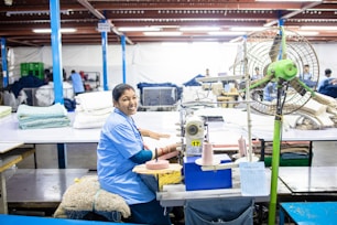 A woman is sewing fabric in a factory.