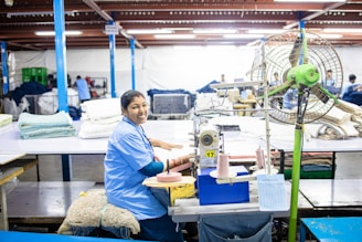 A woman is sewing fabric in a factory.