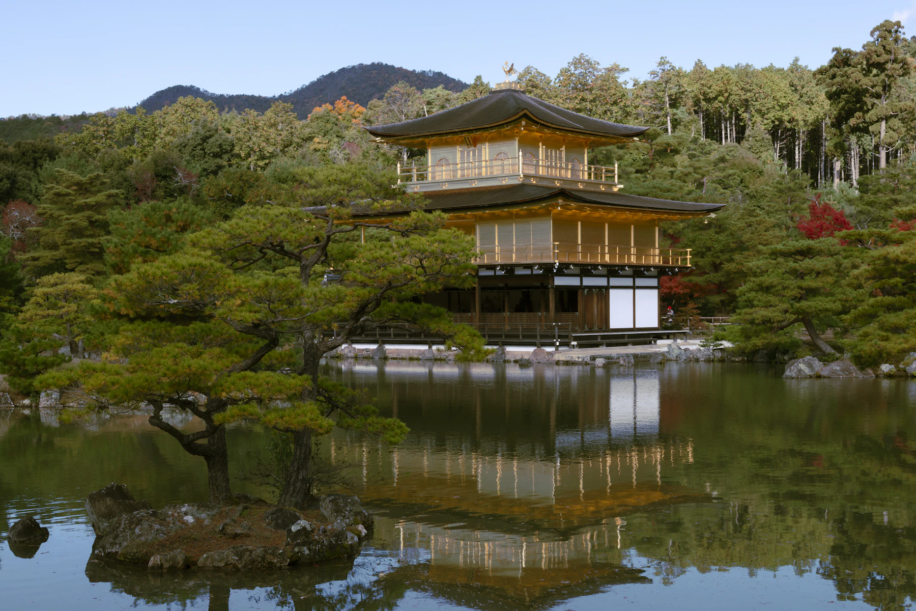 Goldener Pavillon Kinkaku-ji mit Spiegelung im Teich und bewaldeten Hügeln