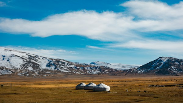 Yurts sit on a steppe before snowy mountains — Ulaanbaatar, Mongolia