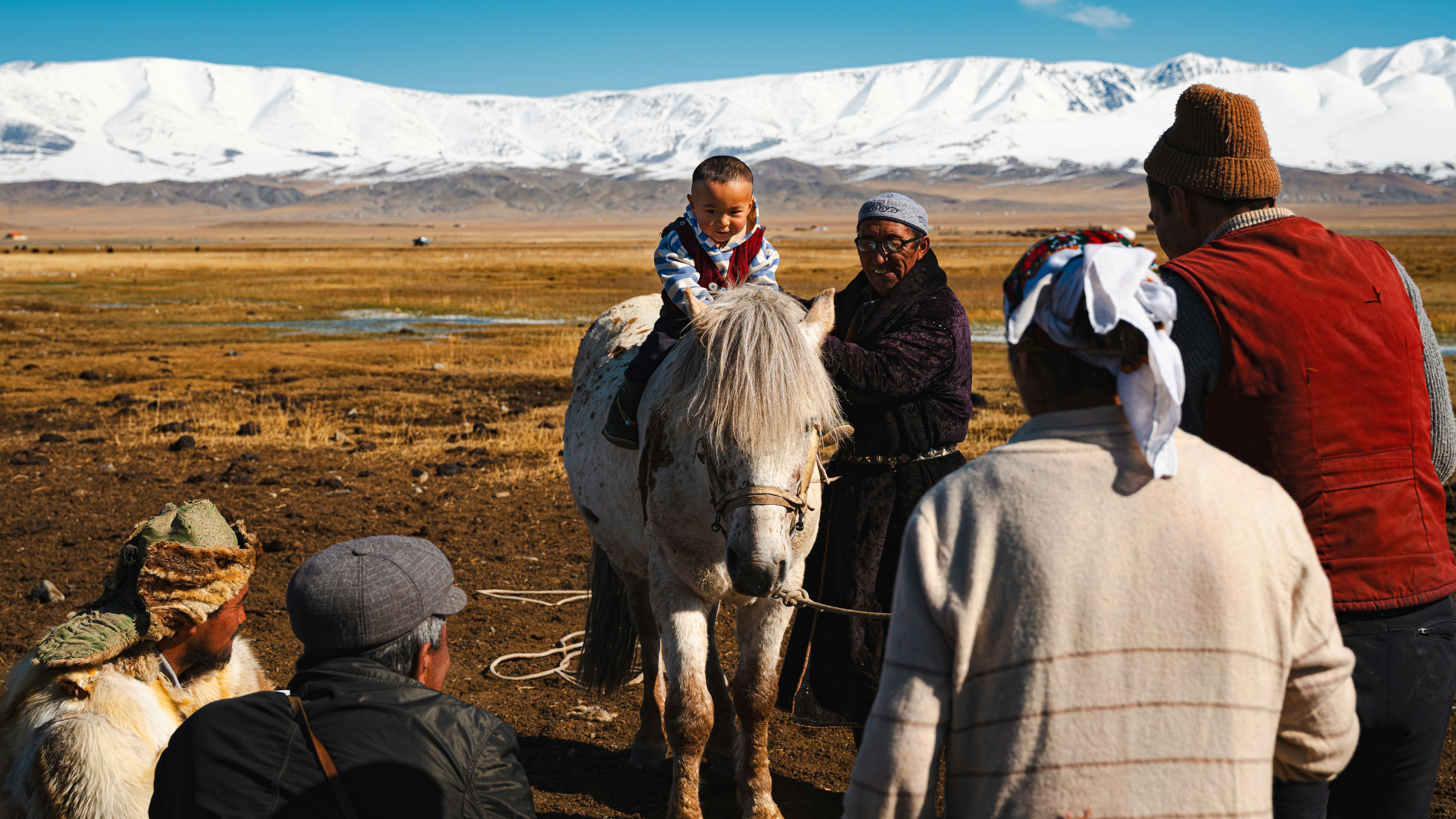 A child rides a horse with family watching.