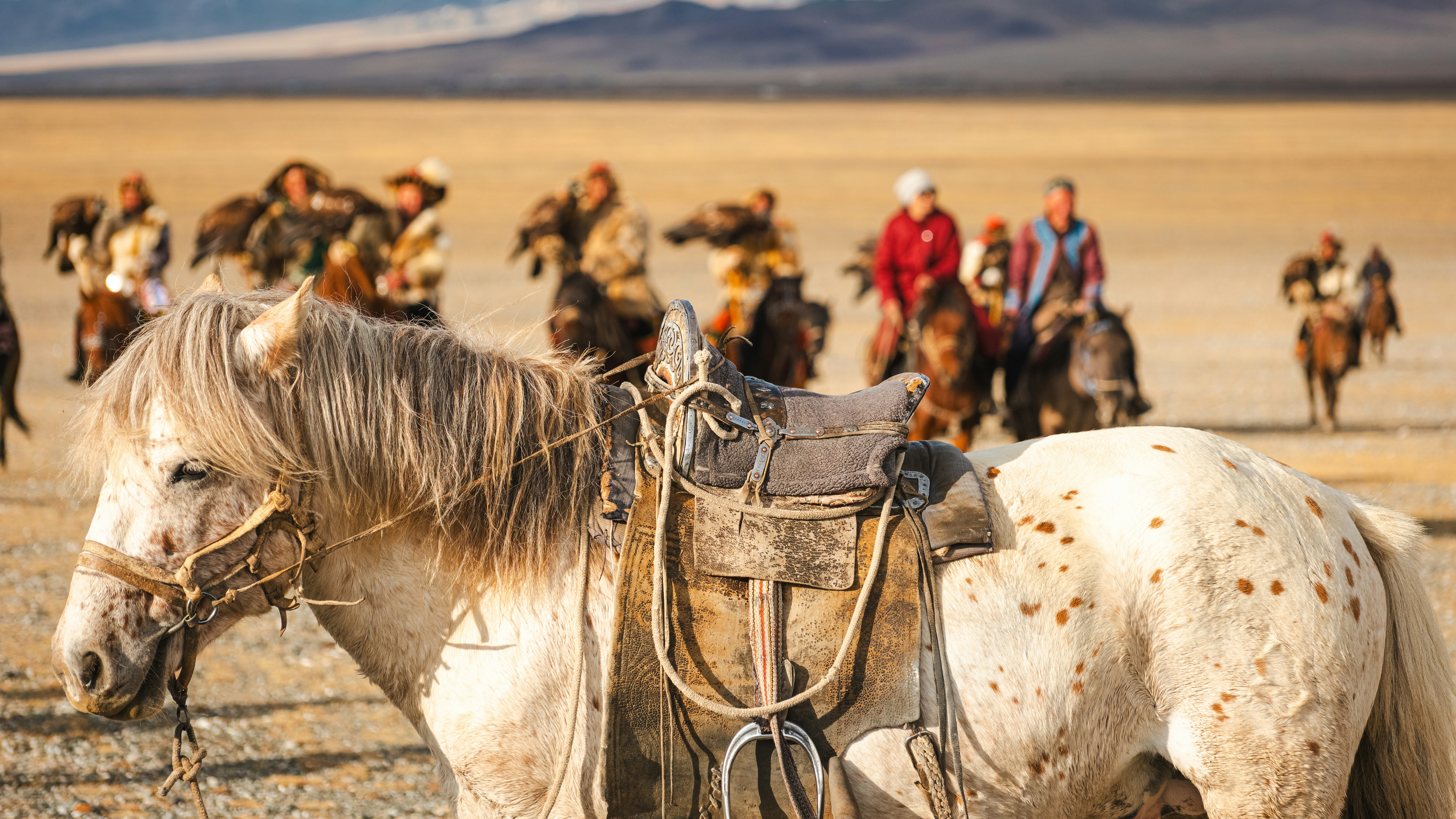Horses and riders traverse the arid landscape together.