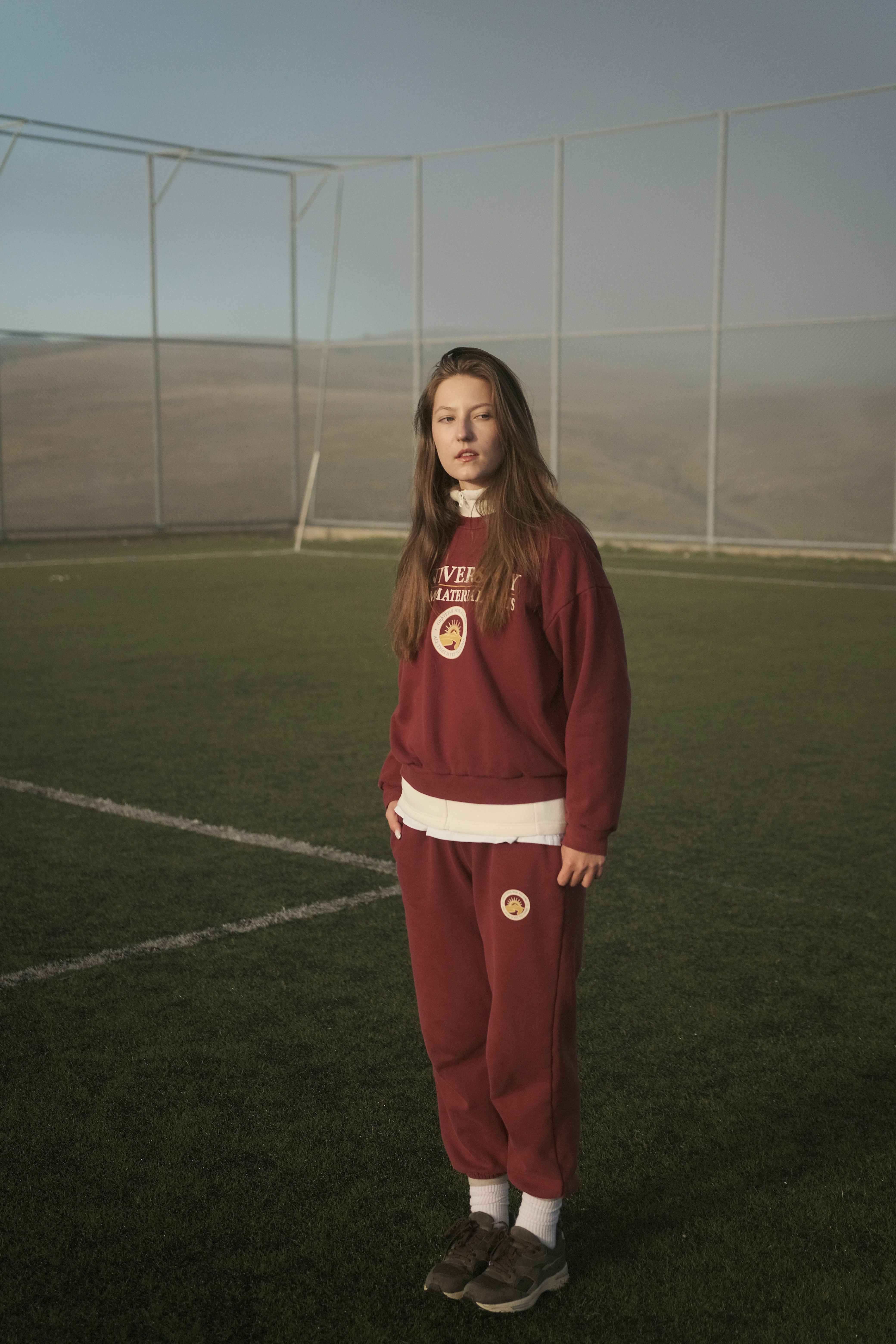 A woman stands on a soccer field.