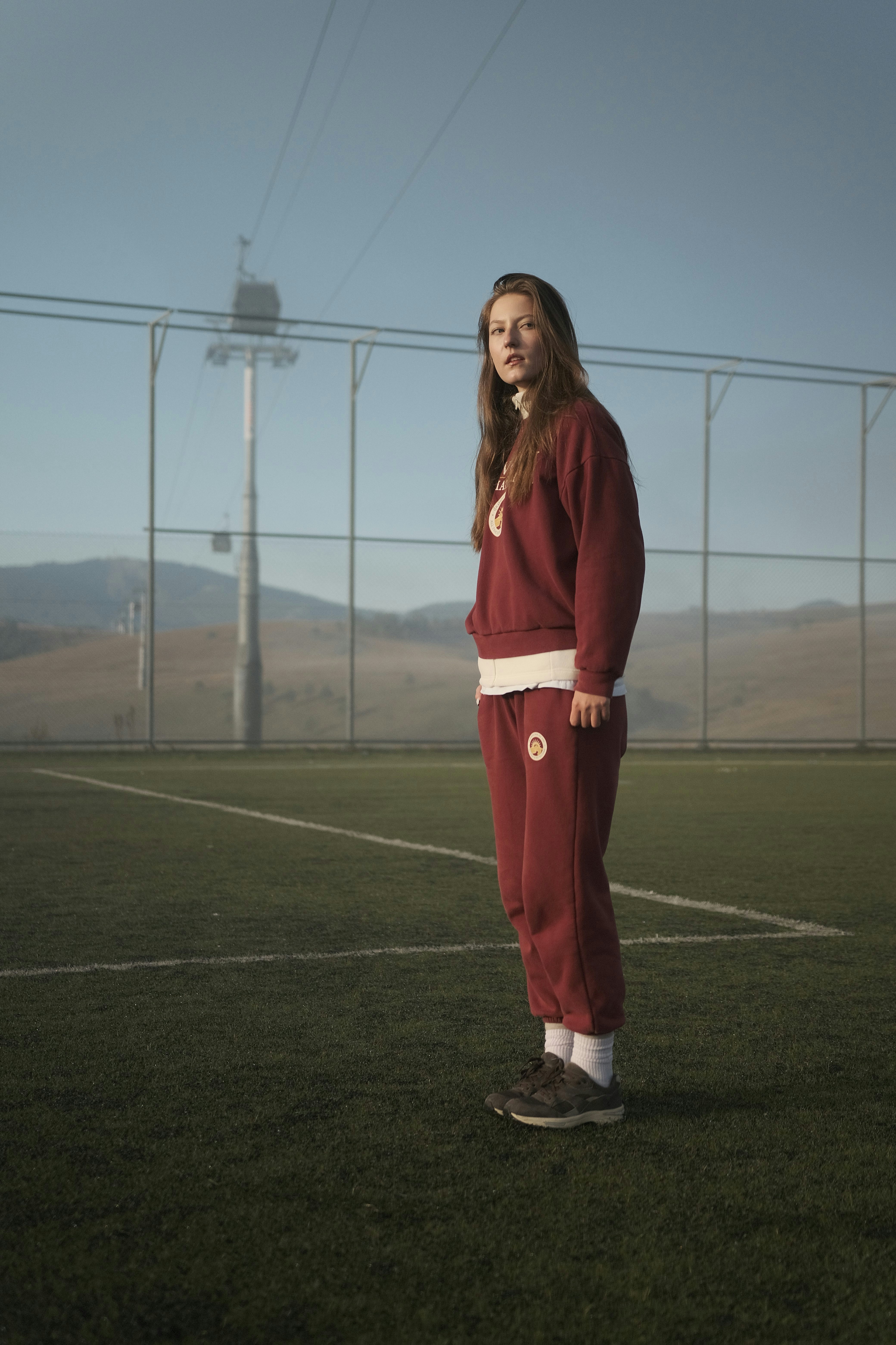 Woman stands on a field near a cable car.