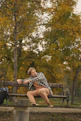 Man relaxes on a park bench surrounded by fall foliage.