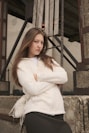 A young woman stands with arms crossed.