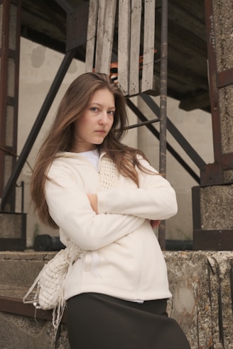 A young woman stands with arms crossed.