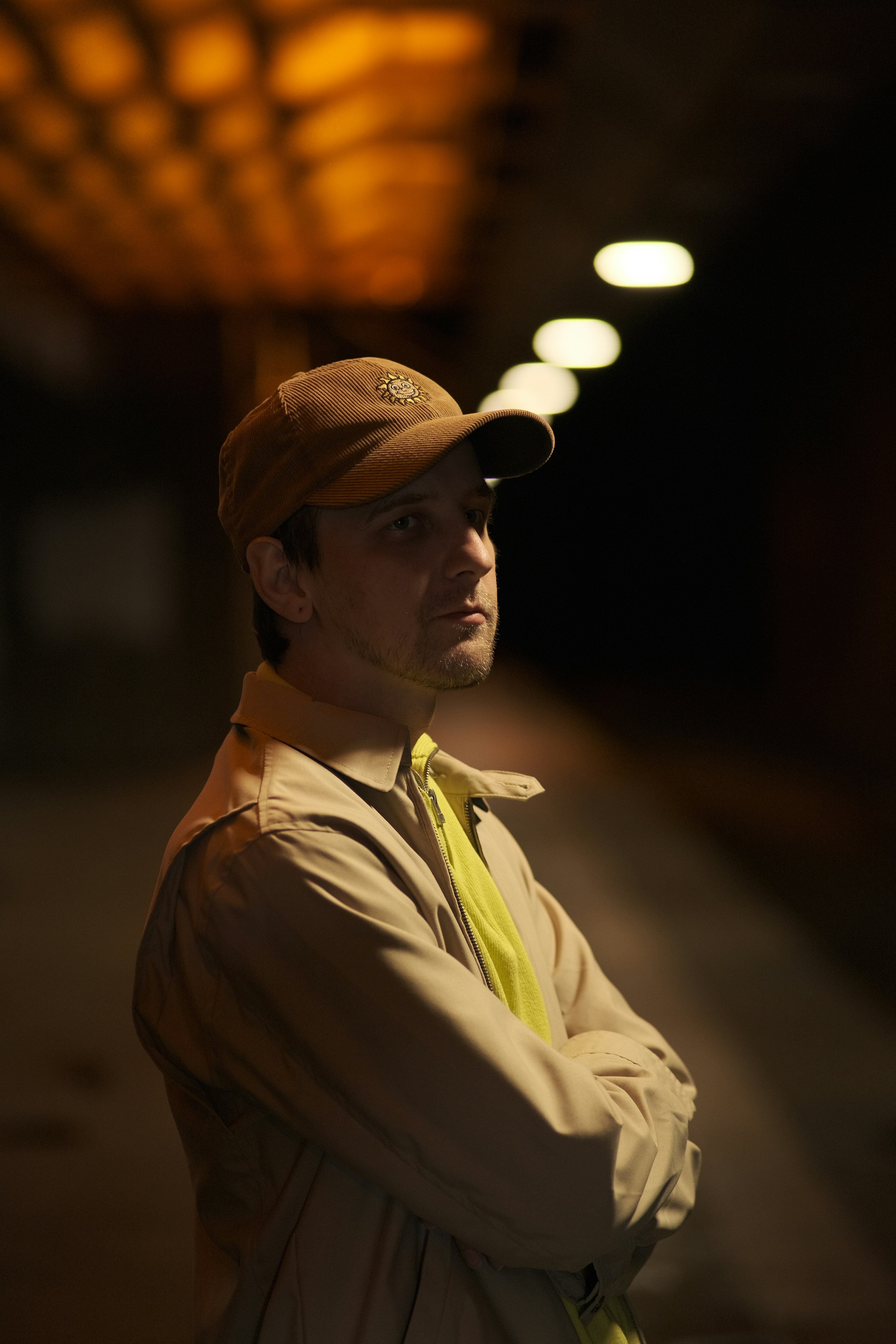 Man stands at night with arms crossed.