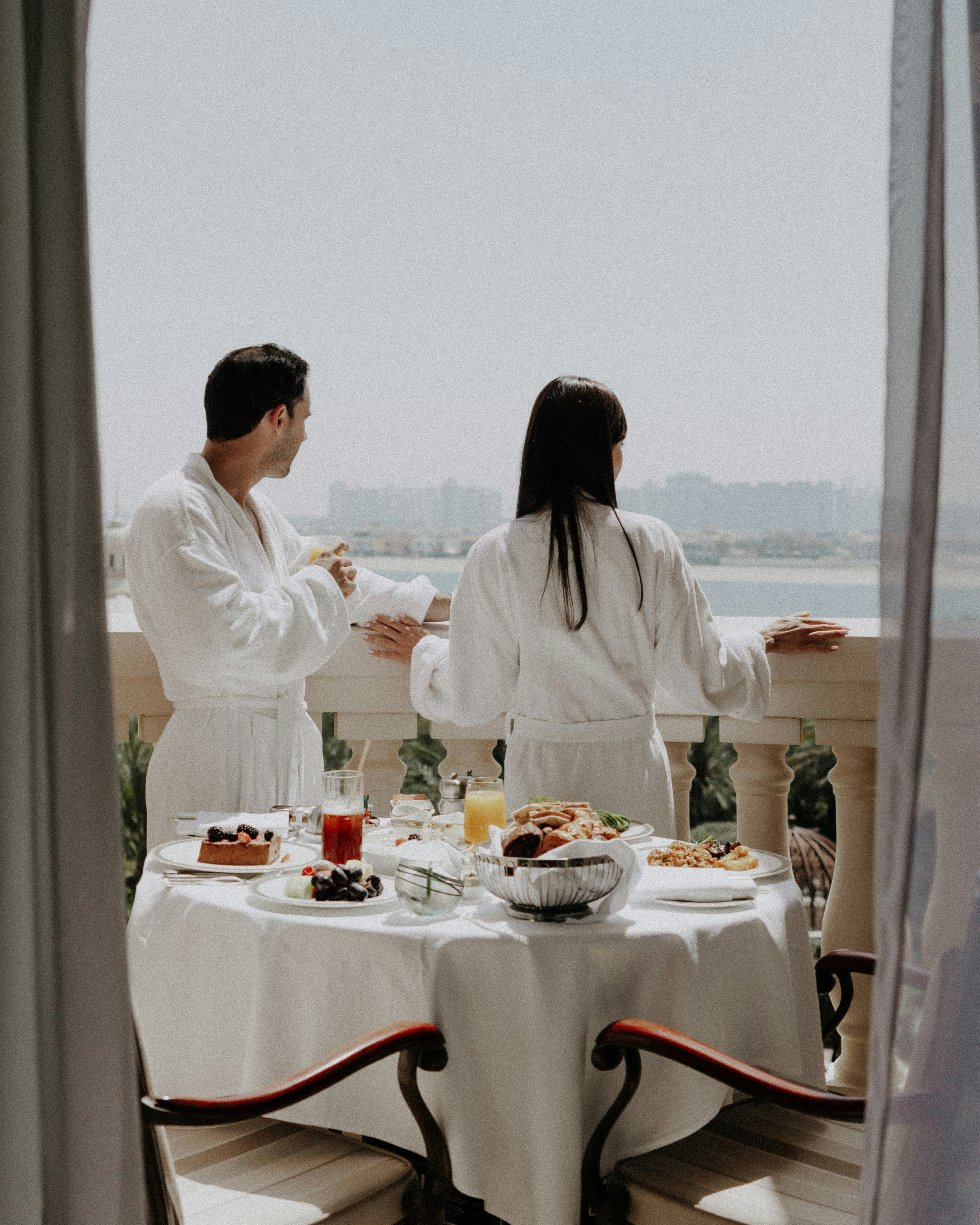 Couple enjoys breakfast on a balcony with a view.
