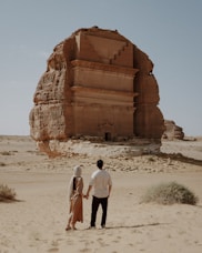 Couple holds hands, admiring an ancient monument.