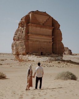 Couple holds hands, admiring an ancient monument.