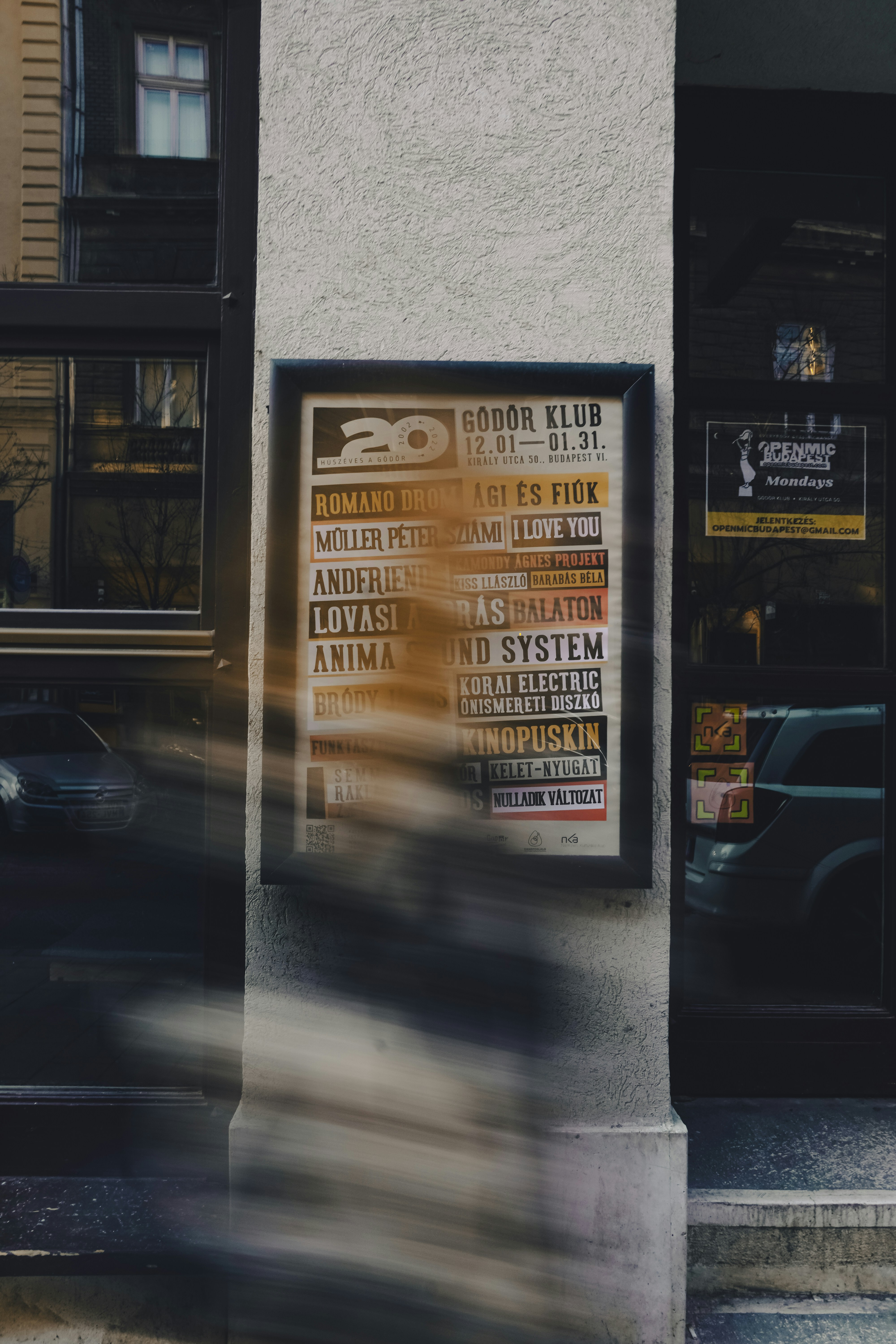 A concert poster hangs on a building's facade.